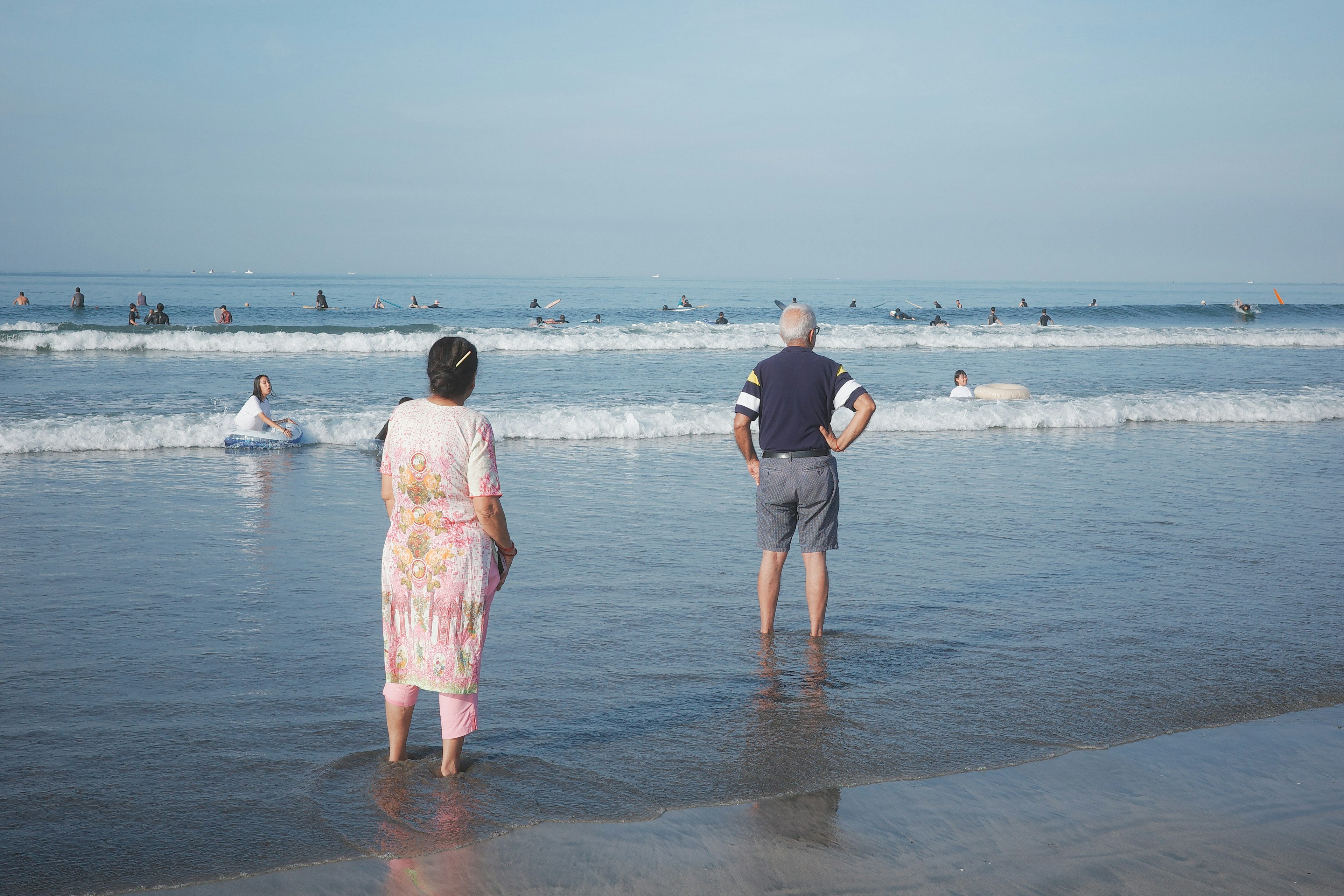 ビーチで海を見つめる男女の後ろ姿