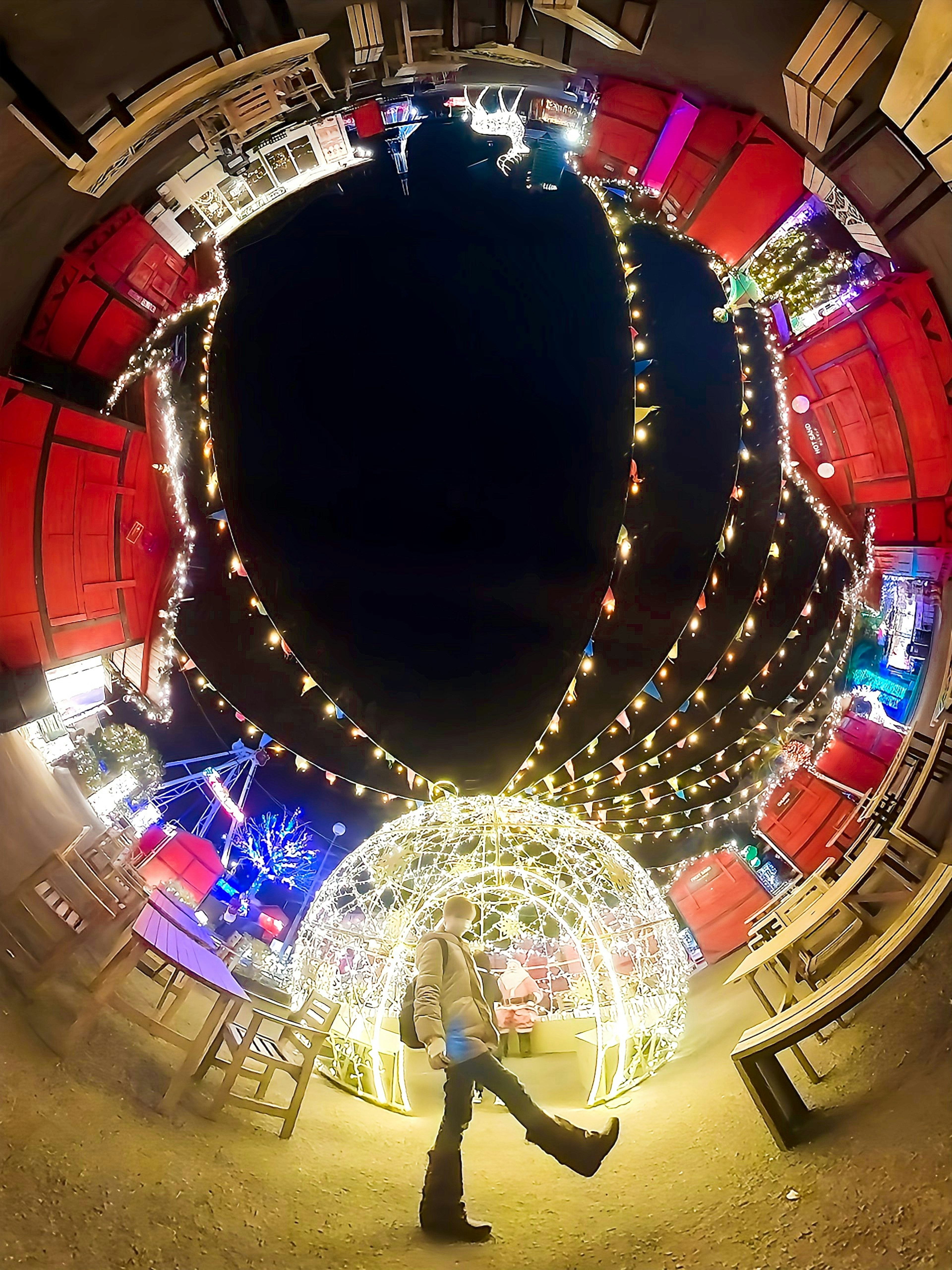 A person walking amidst decorative lights in a vibrant night setting