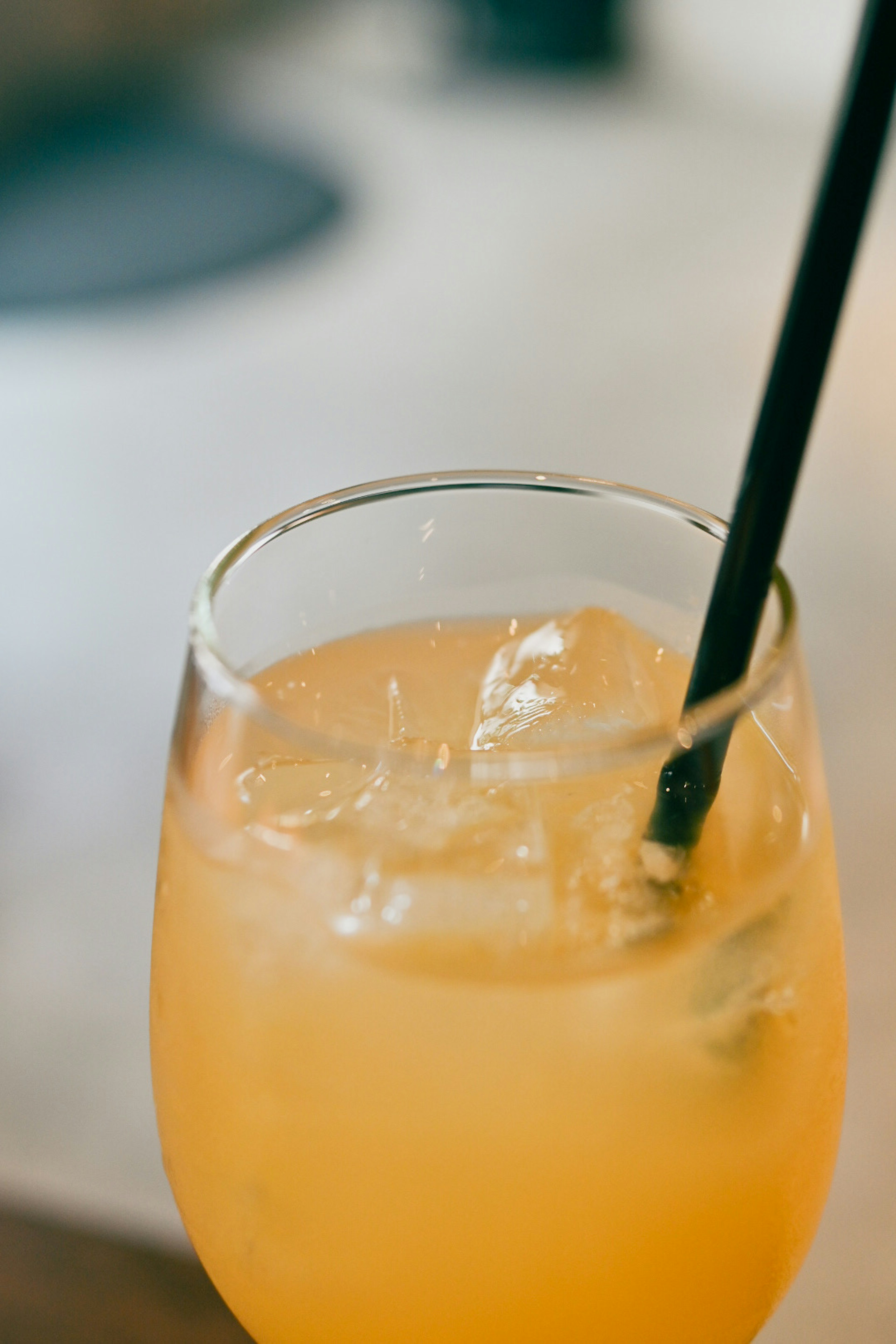 Un vaso de bebida naranja con hielo y una pajita