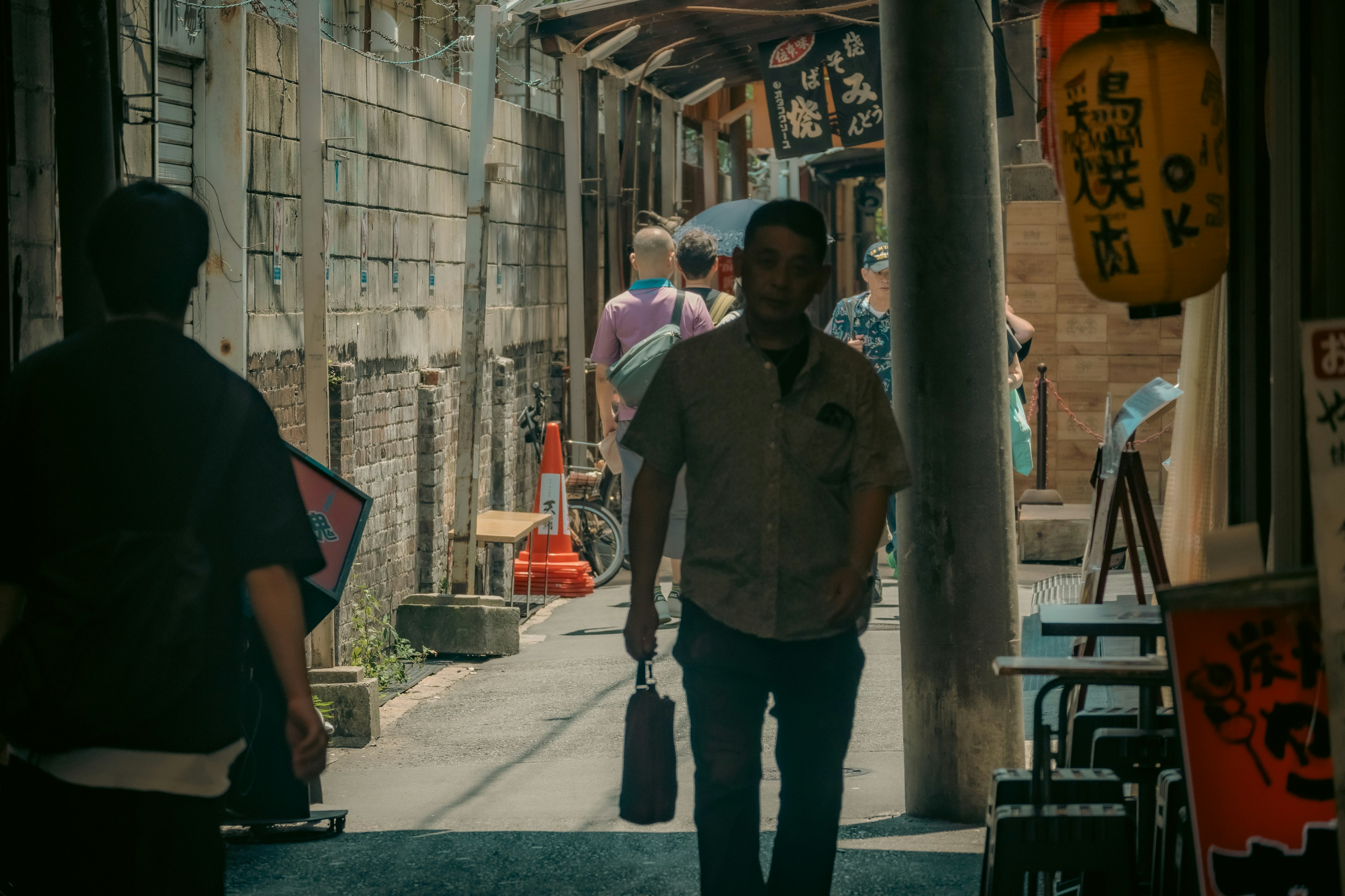 Man walking in a narrow alley with people in the background bright lanterns and old buildings