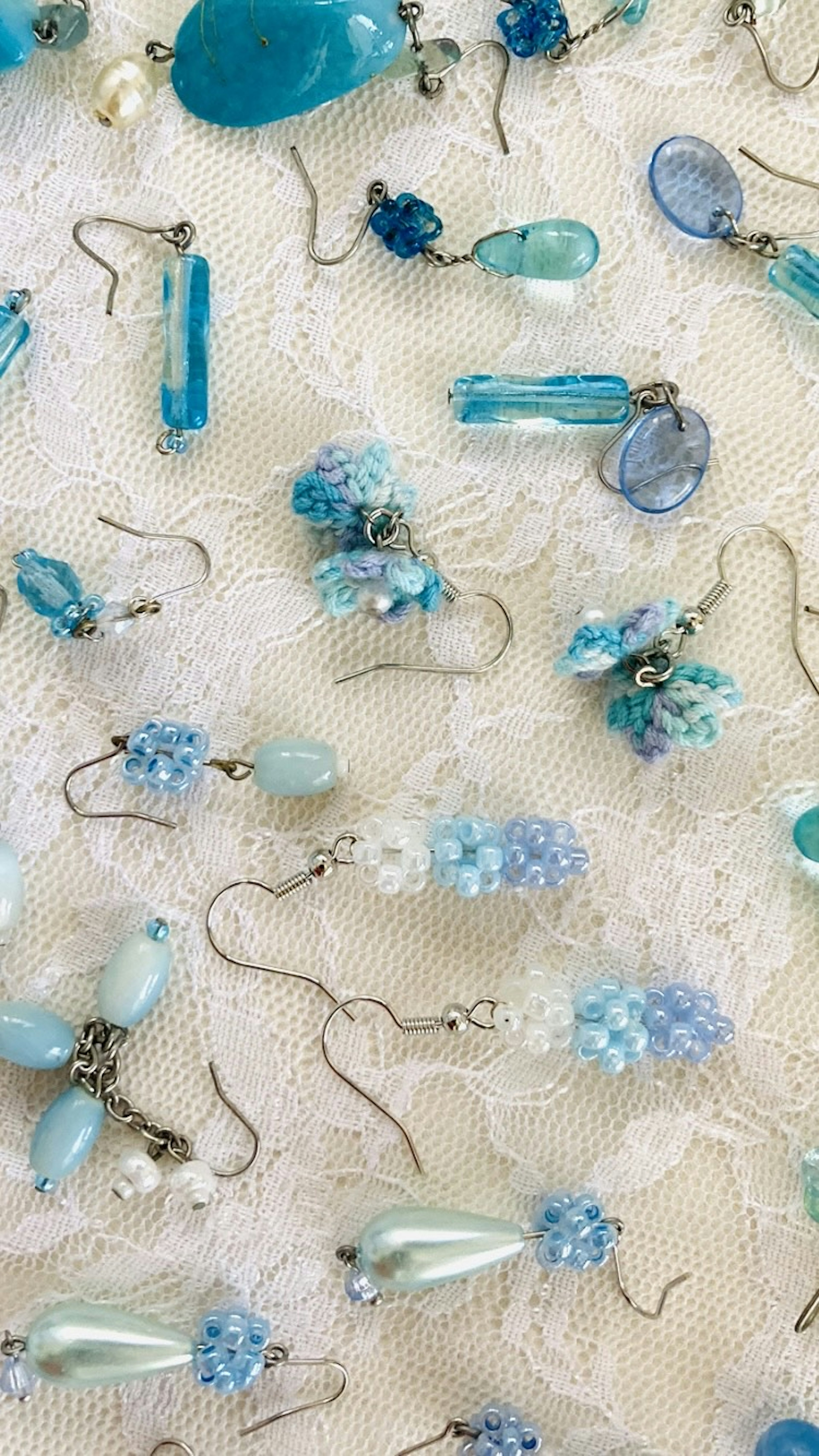 A variety of earrings featuring blue beads and pendants arranged on a light background