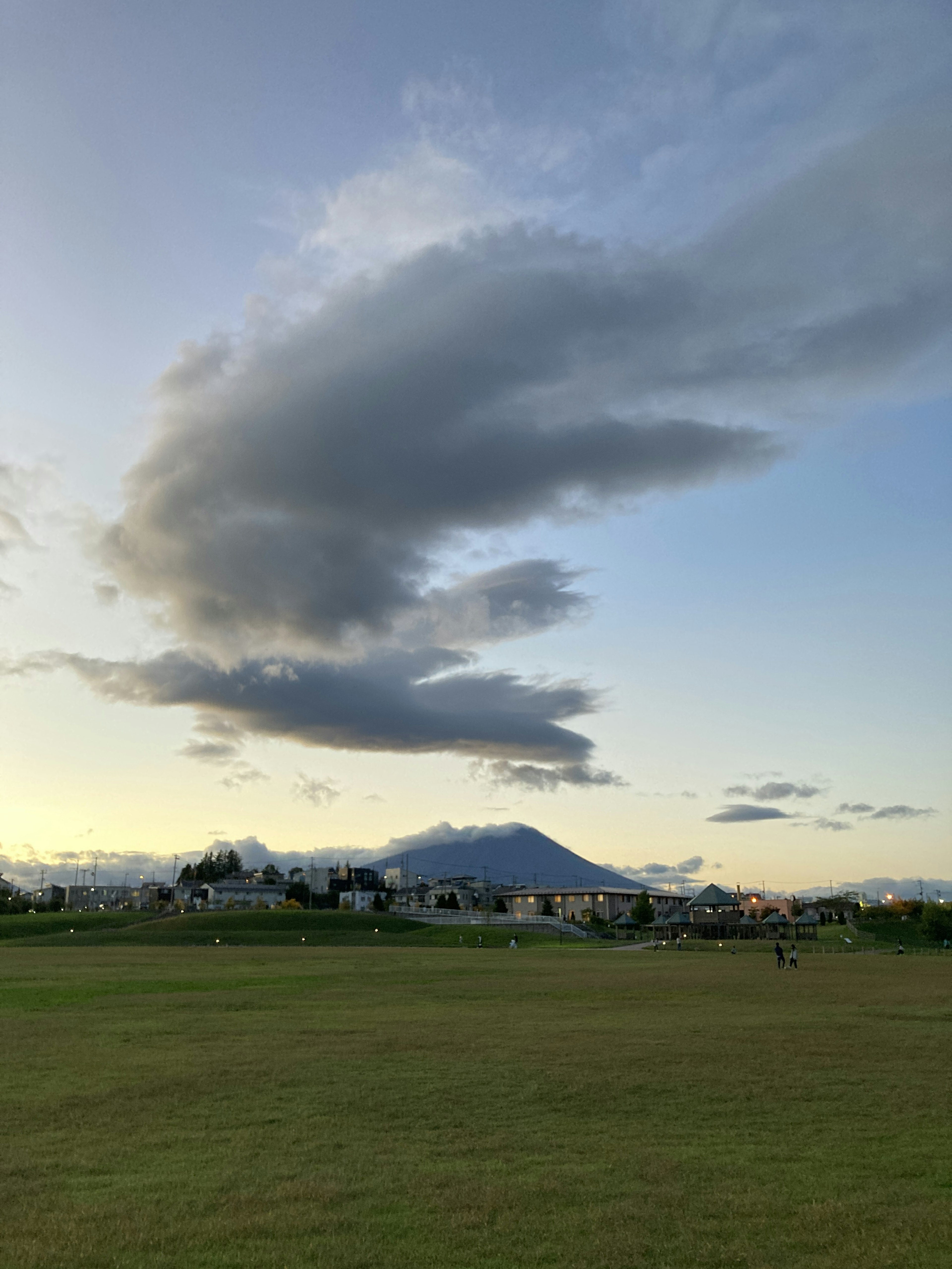 Amplio campo de hierba con nubes impresionantes y una montaña al fondo