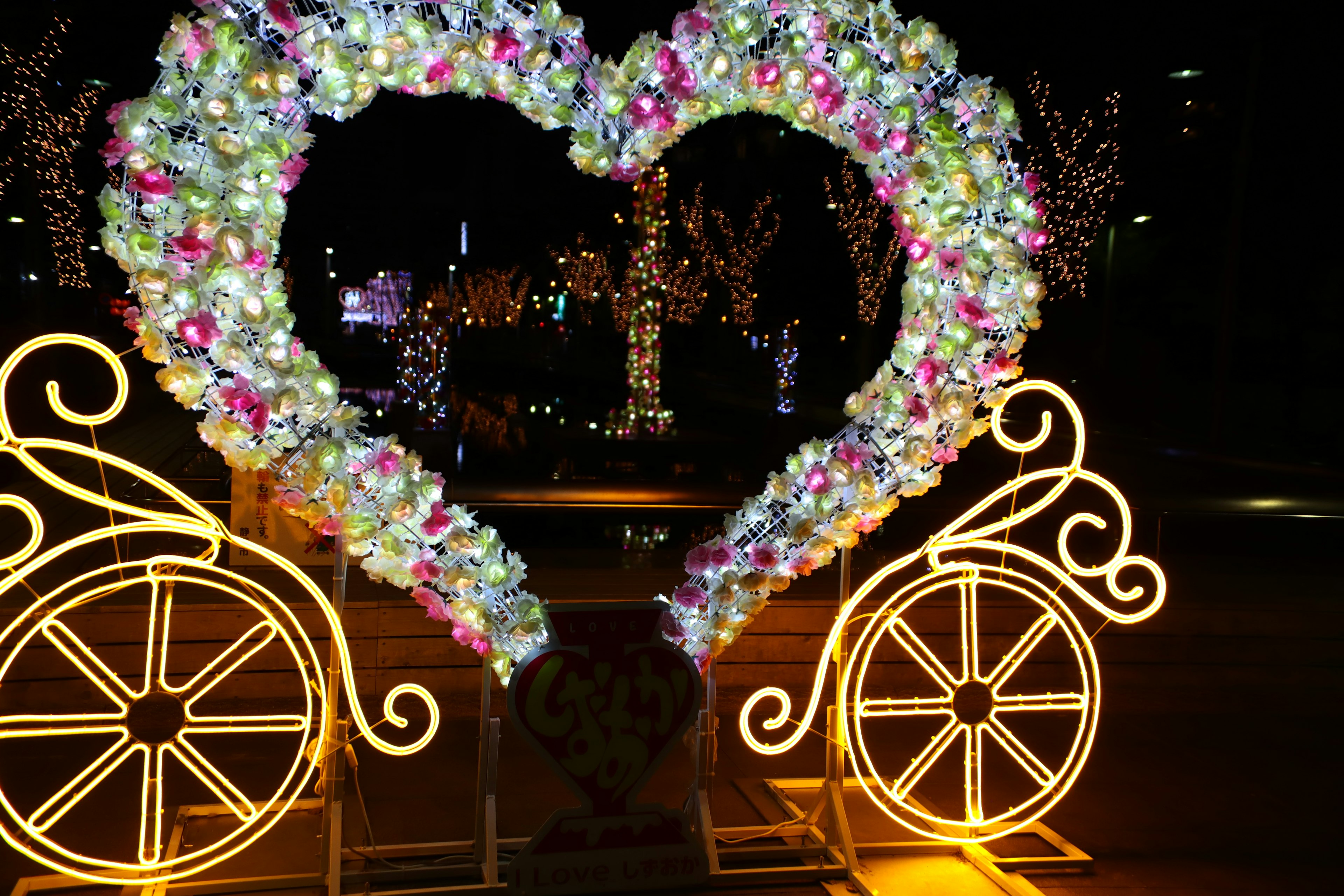 Herzförmige Blumendekoration mit beleuchteten Rädern bei Nacht