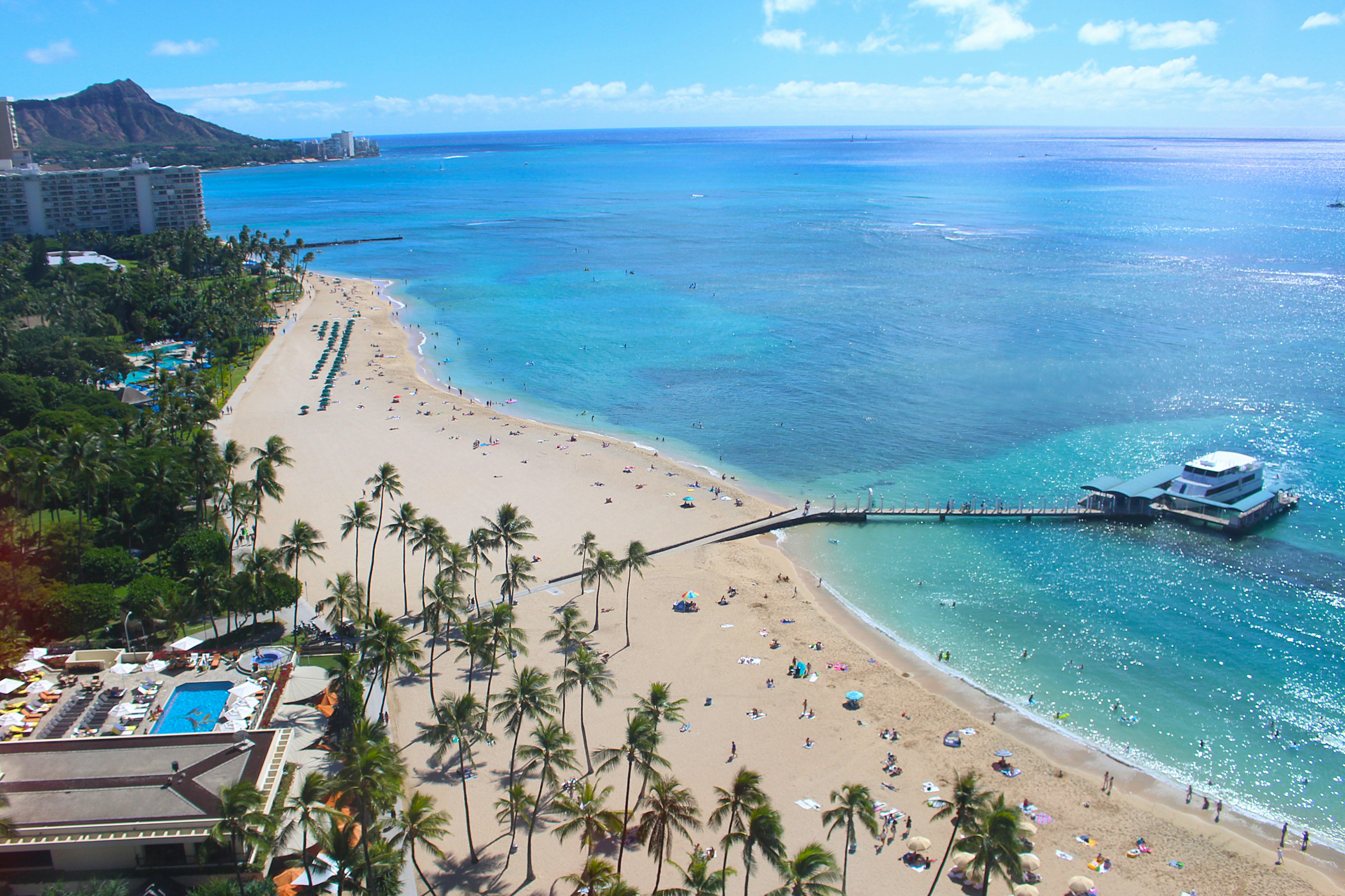 Une vue de plage pittoresque avec océan bleu et sable blanc De nombreuses personnes profitant de la plage près des palmiers et d'un quai