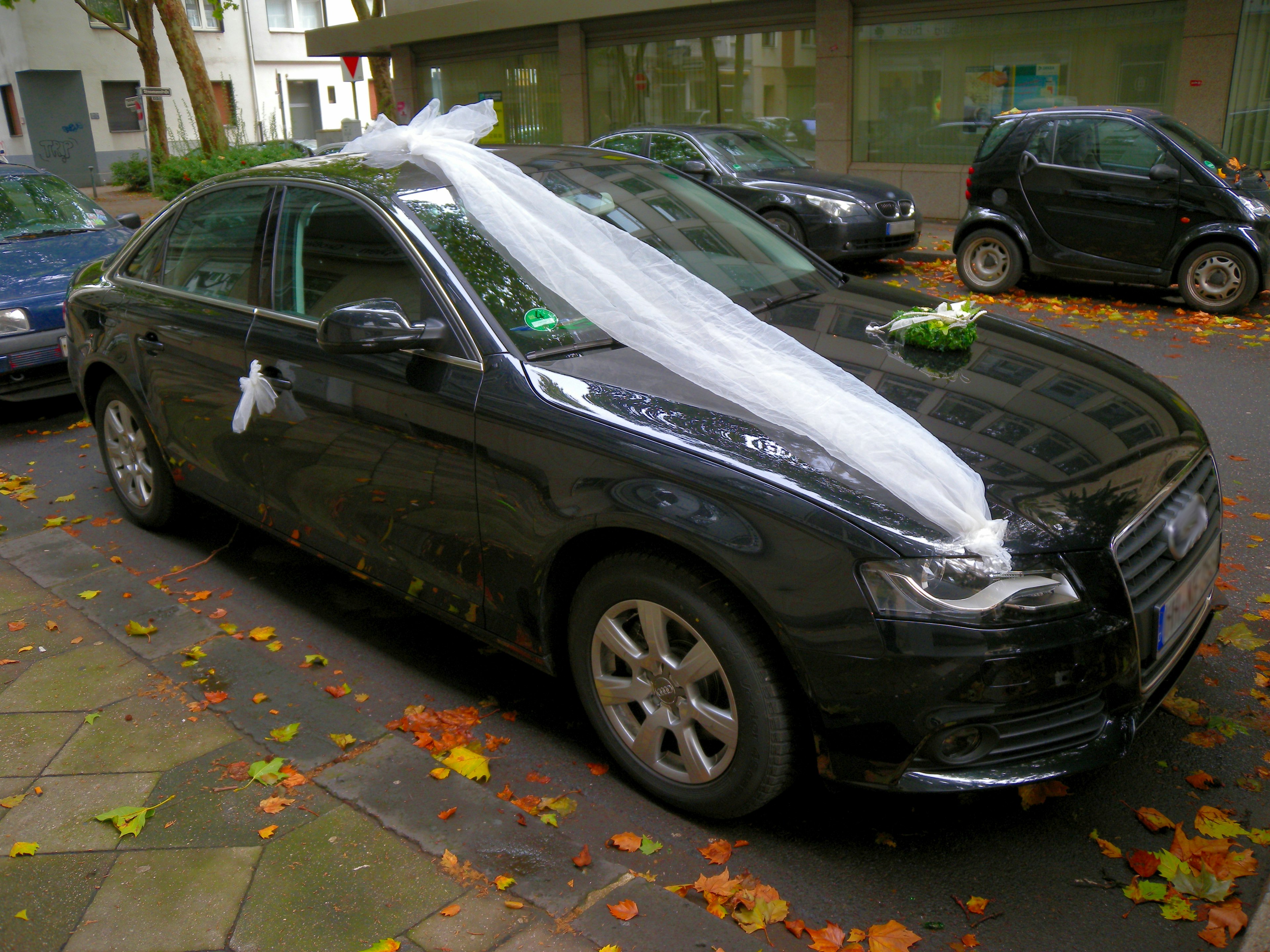 Coche negro decorado con cintas blancas y flores para una boda