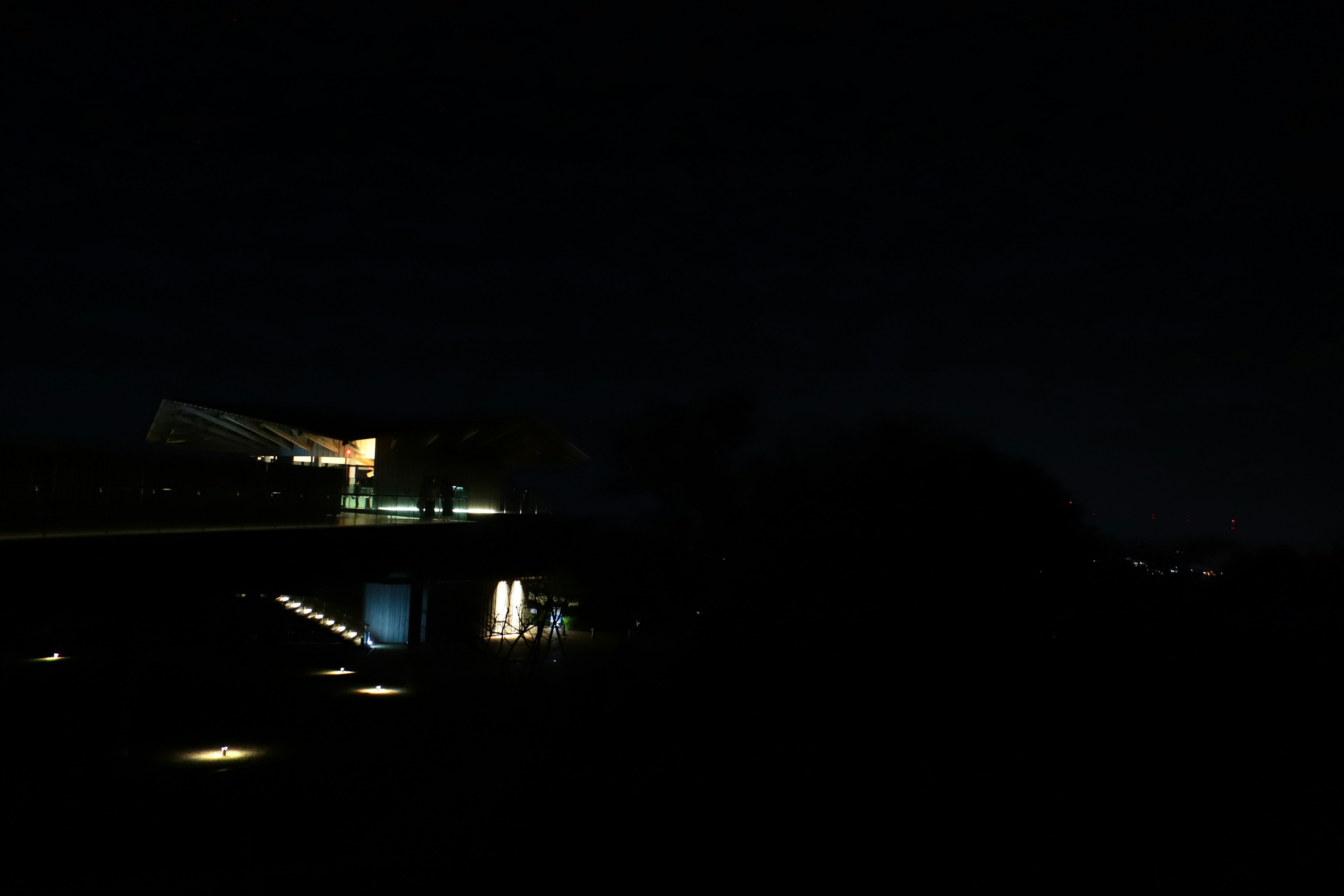 Luces de un edificio iluminadas por la noche en un paisaje oscuro