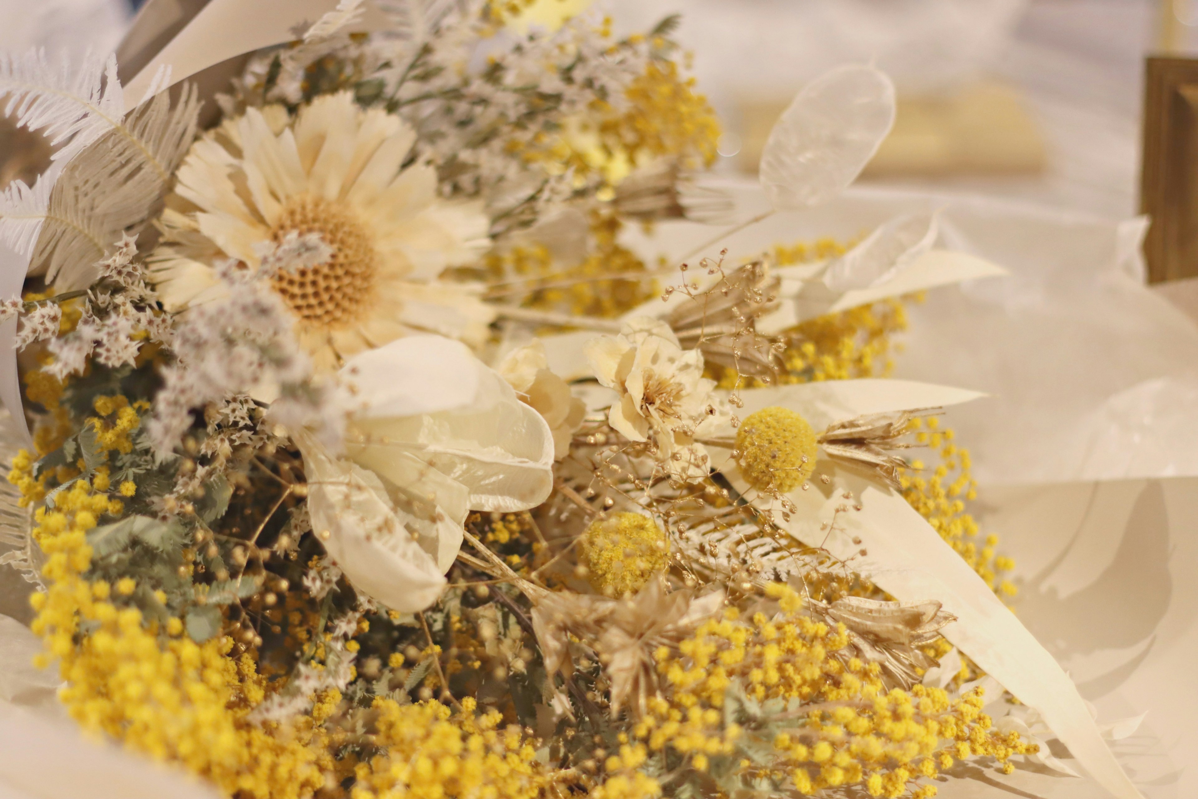 Close-up of a bouquet featuring yellow flowers and dried foliage