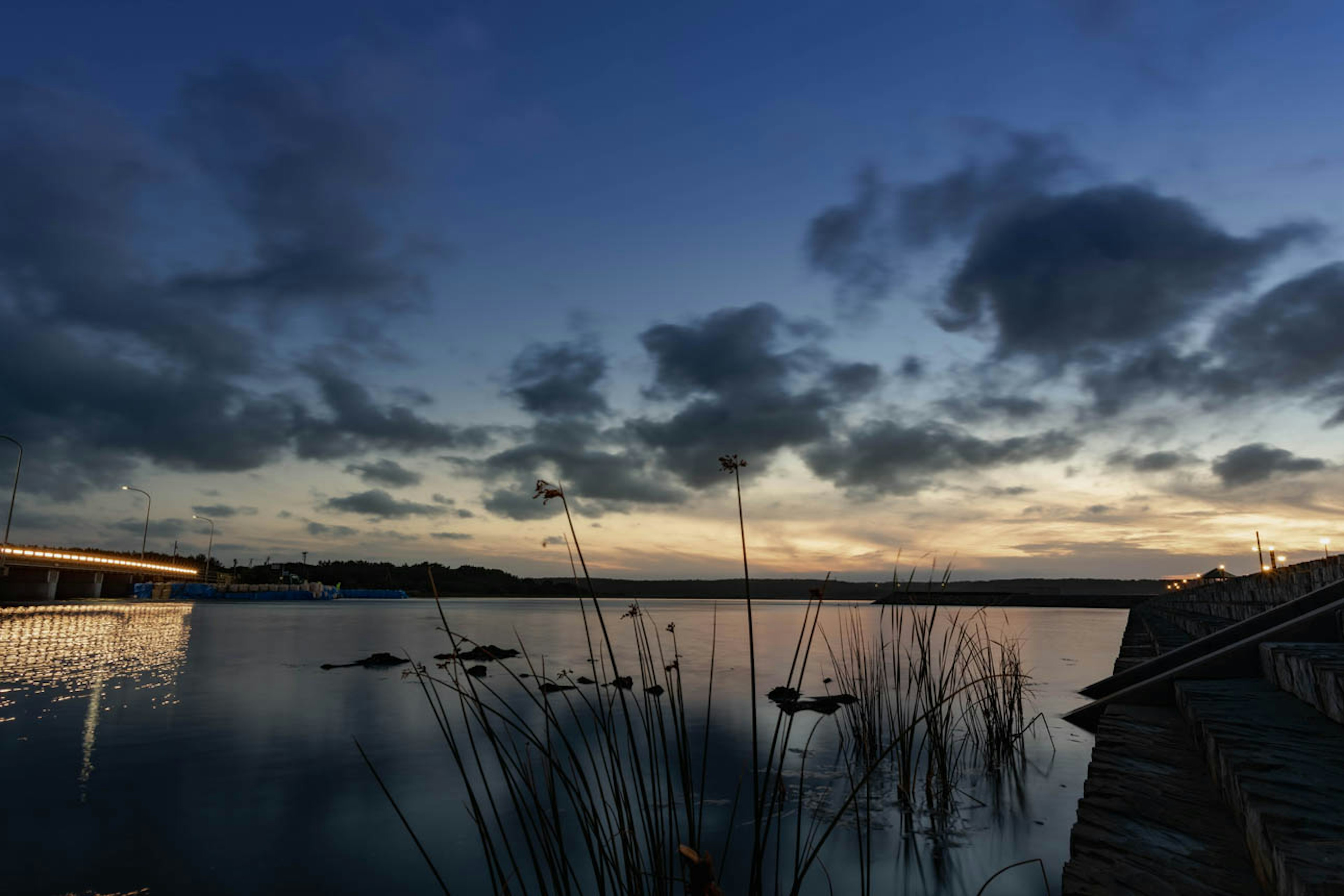 Tranquil lake scene at dusk with clouds reflected on the water and gentle light