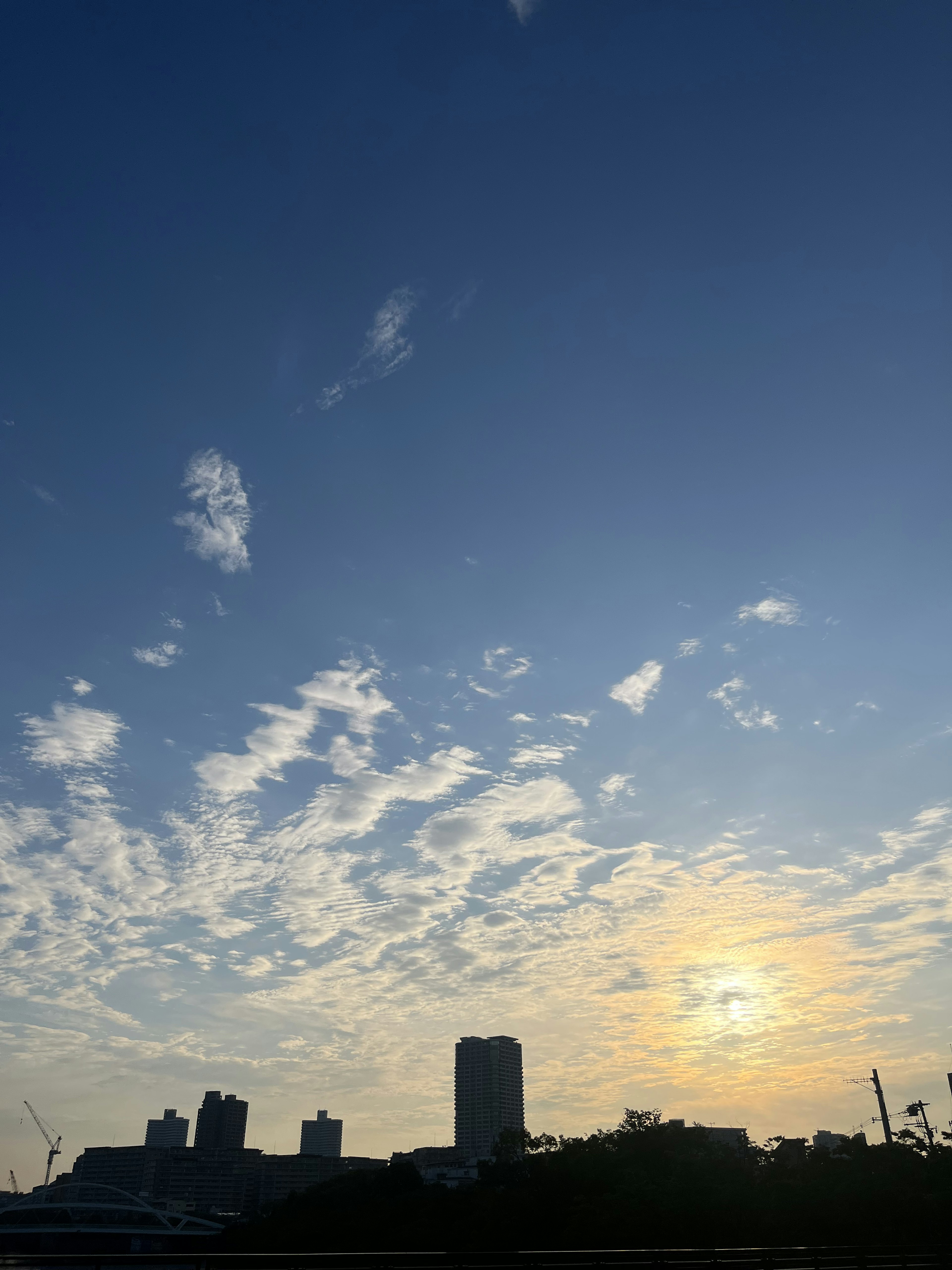 Silueta de edificios contra un cielo azul con nubes al atardecer