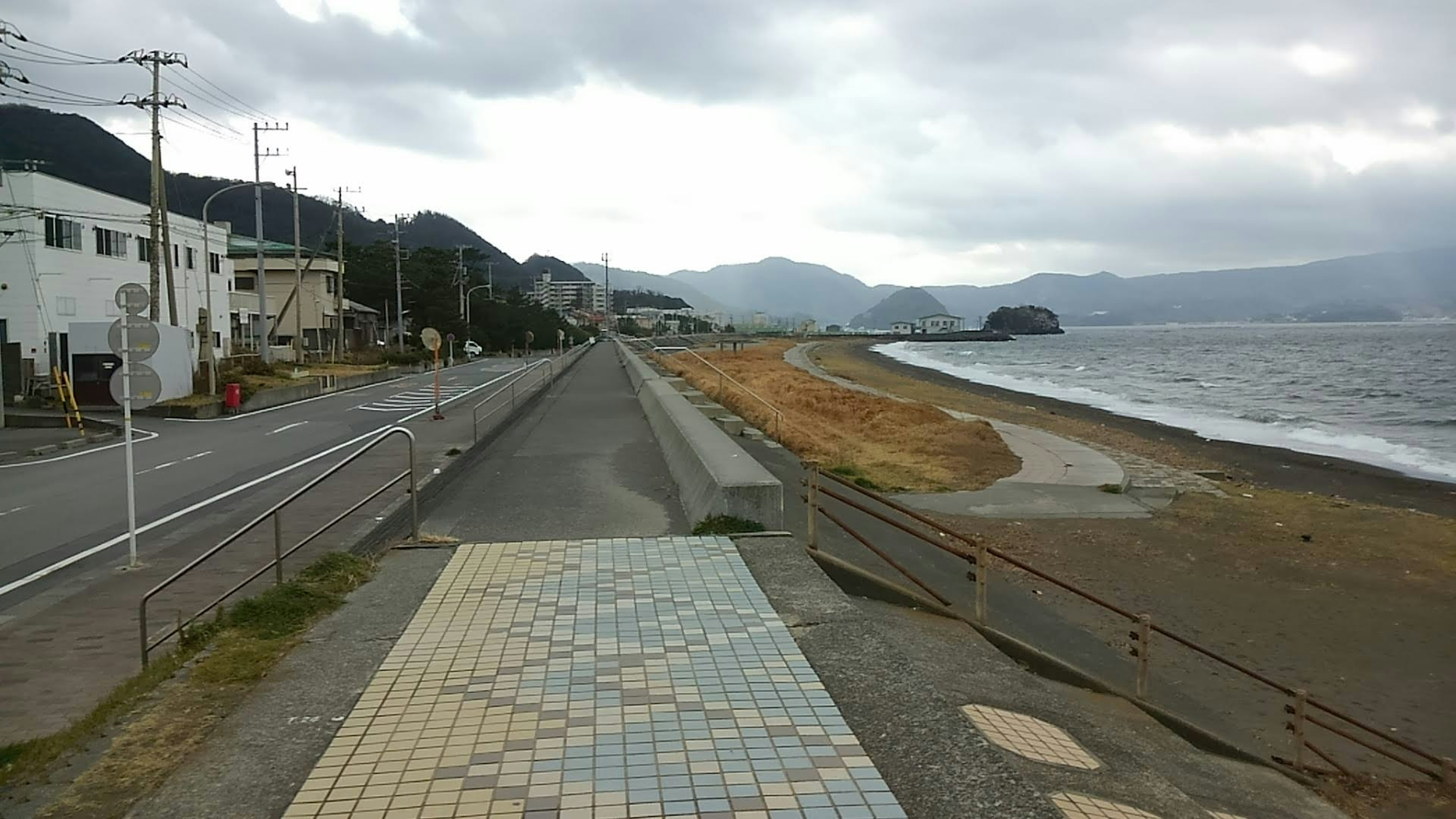 Camino costero con cielo nublado y vista a la playa