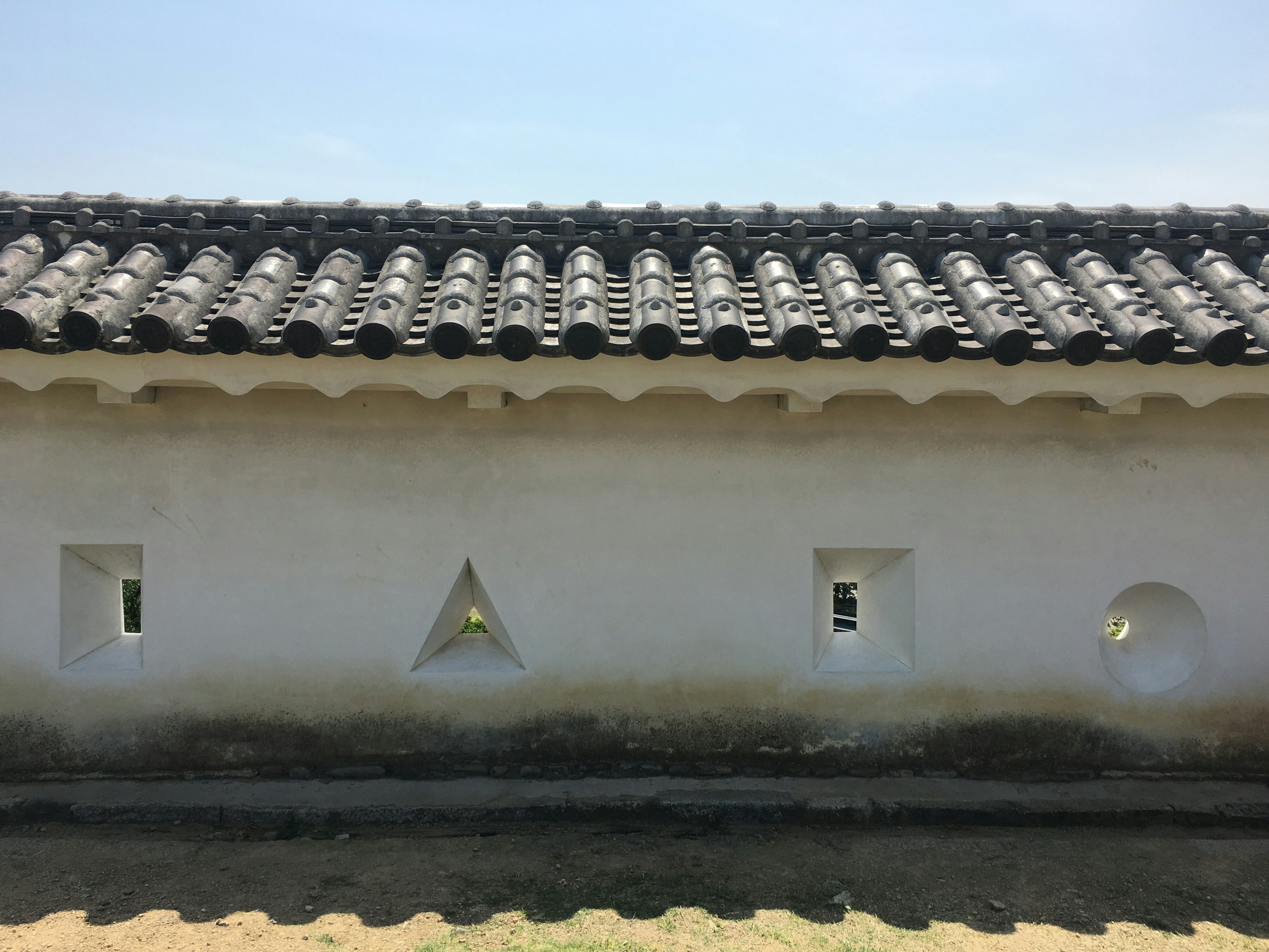 Traditional building with a white wall featuring triangular and circular windows