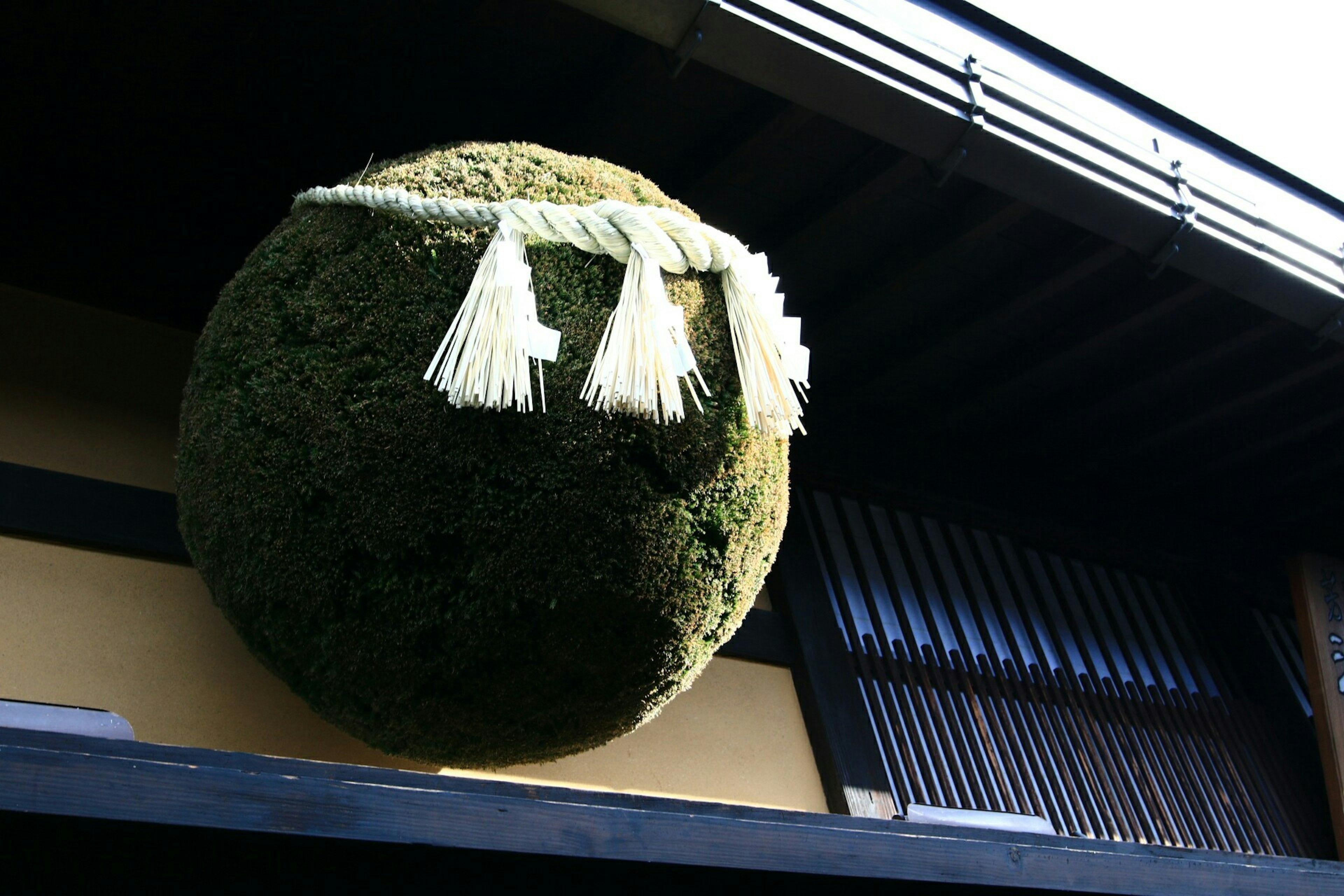 Decoración esférica verde tradicional con borlas blancas en el exterior de un edificio japonés