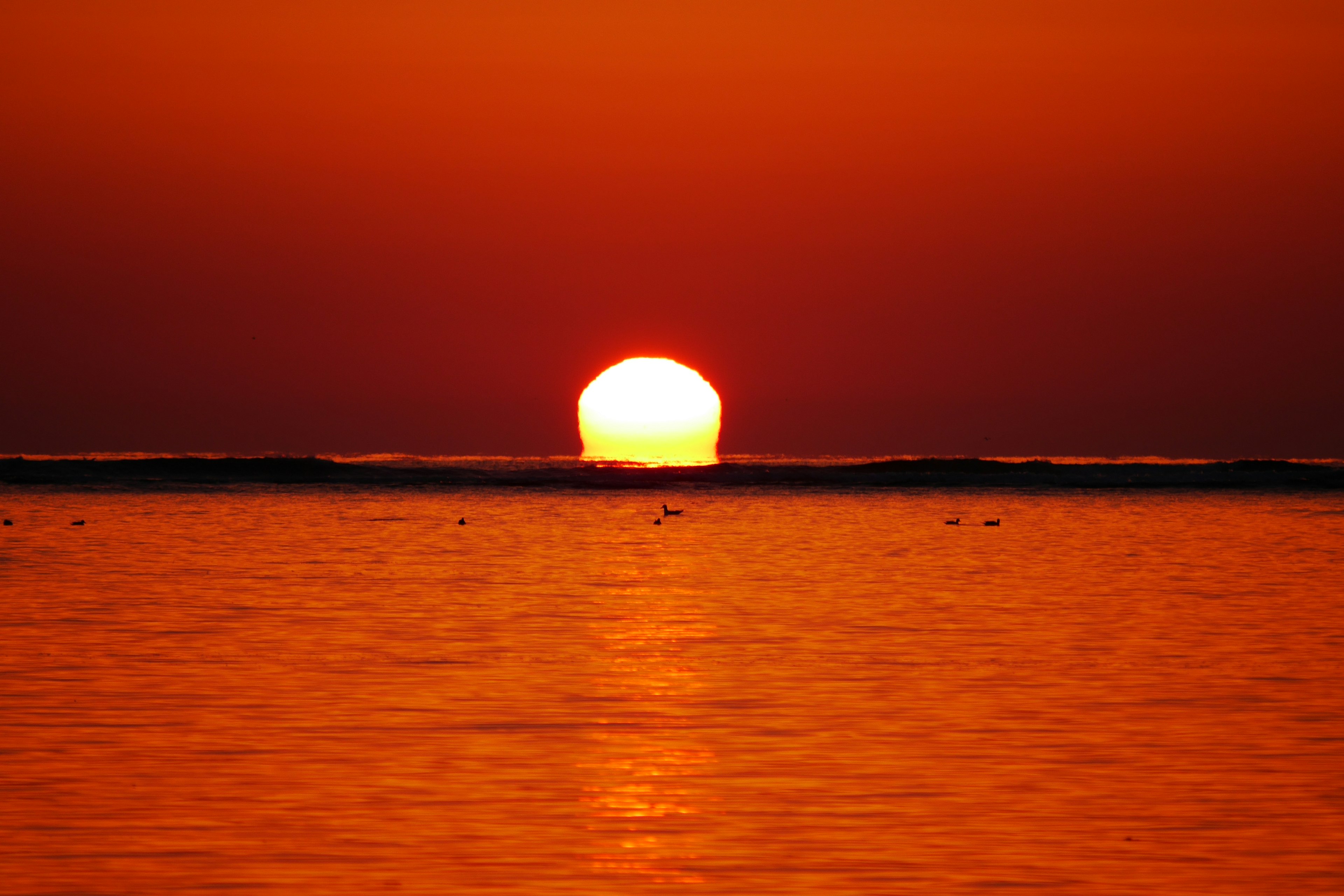 Un hermoso atardecer sobre el océano con un cielo naranja y reflejos en el agua