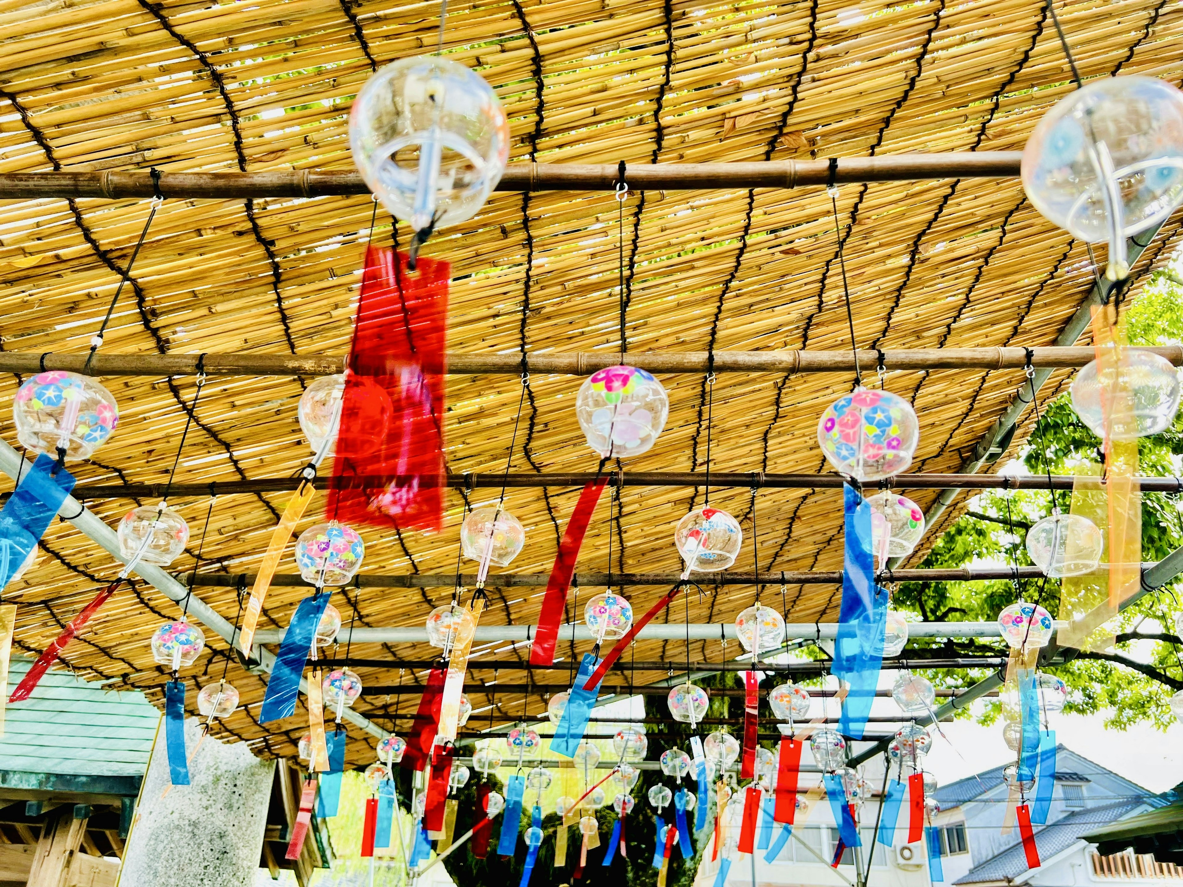 Campanas de viento coloridas y cintas colgando bajo un techo de bambú