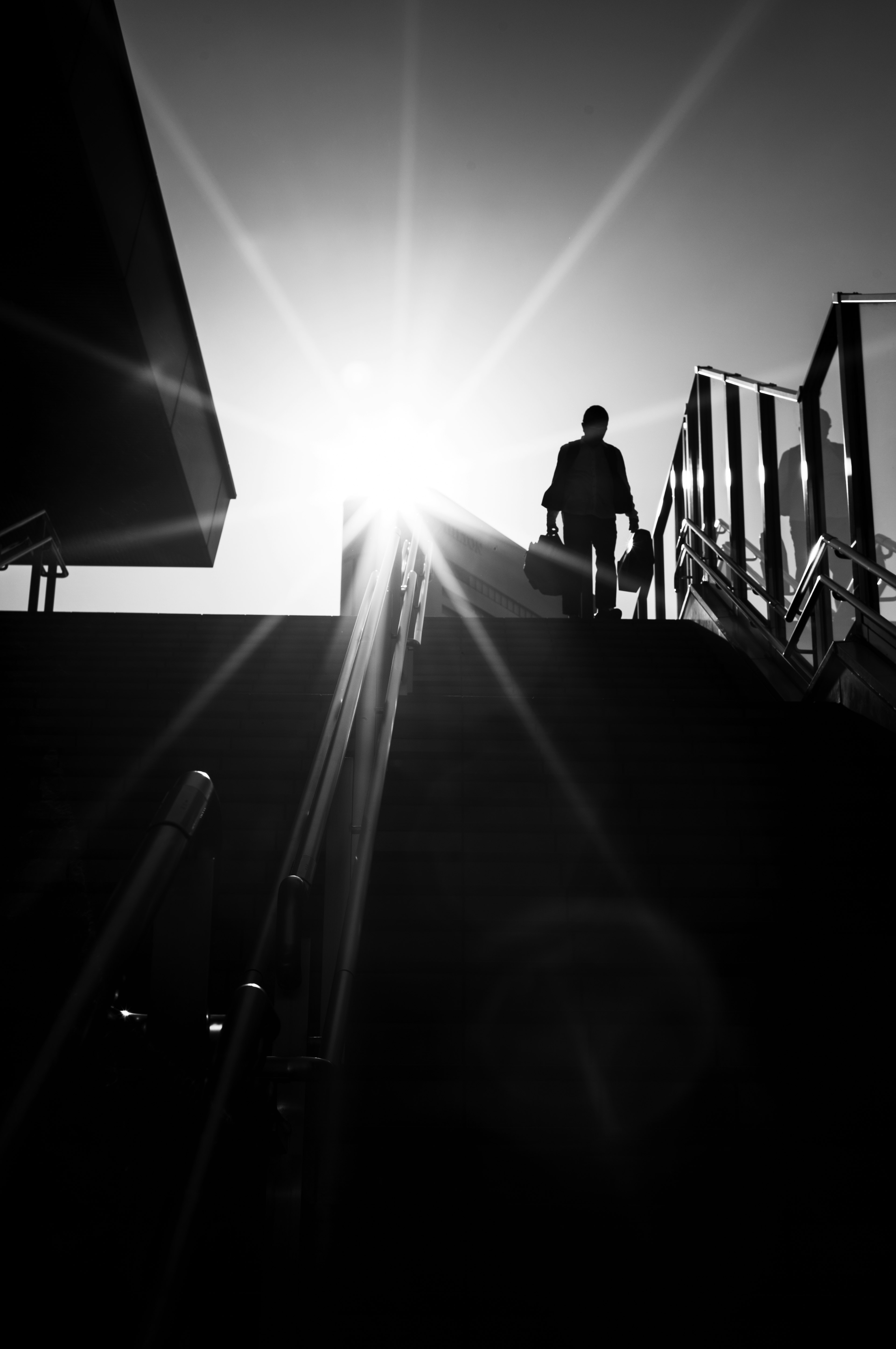 Silhouette of a person ascending stairs with sunlight