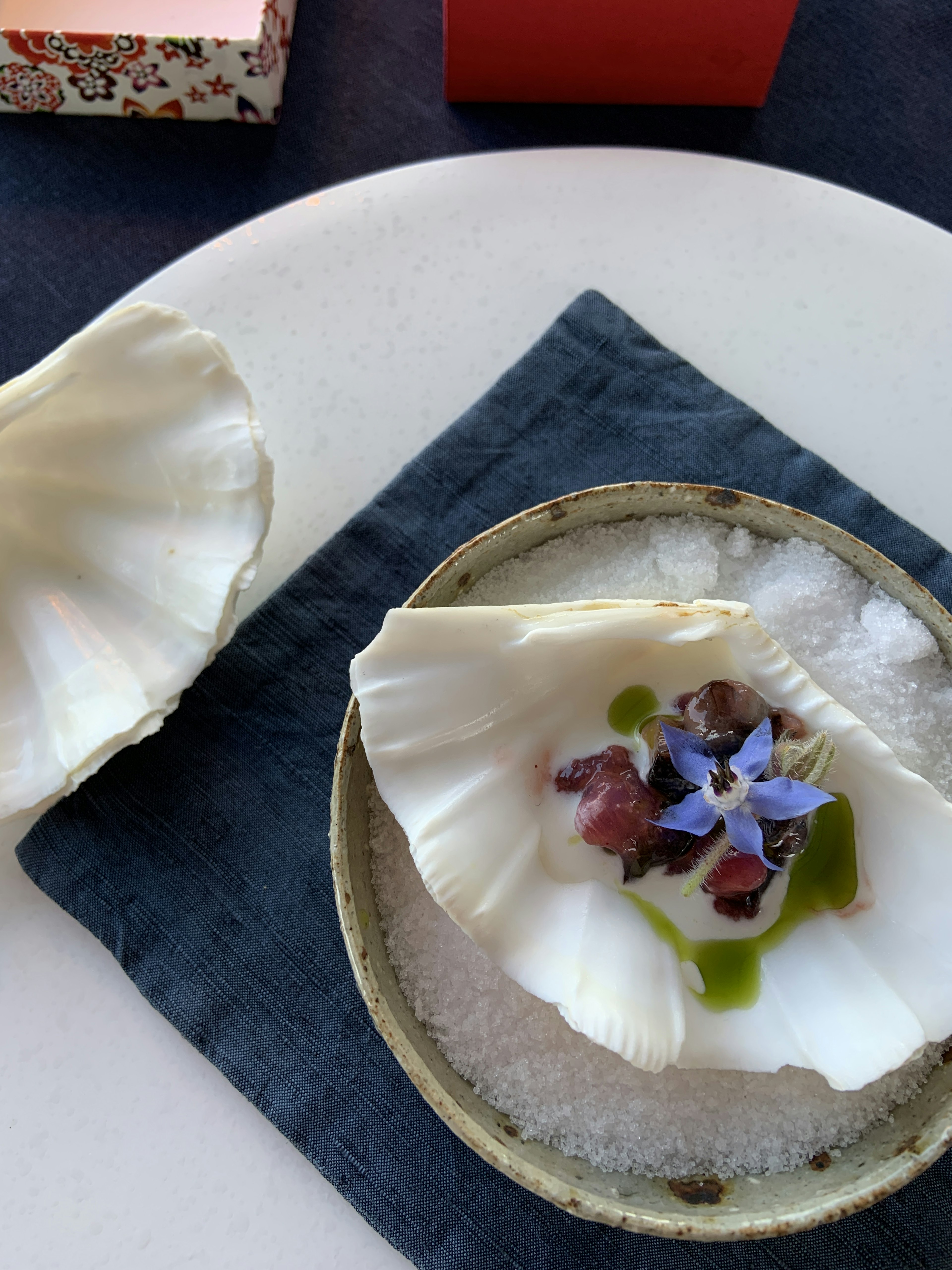 Plat servi dans une coquille blanche sur un lit de sel avec des fleurs comestibles