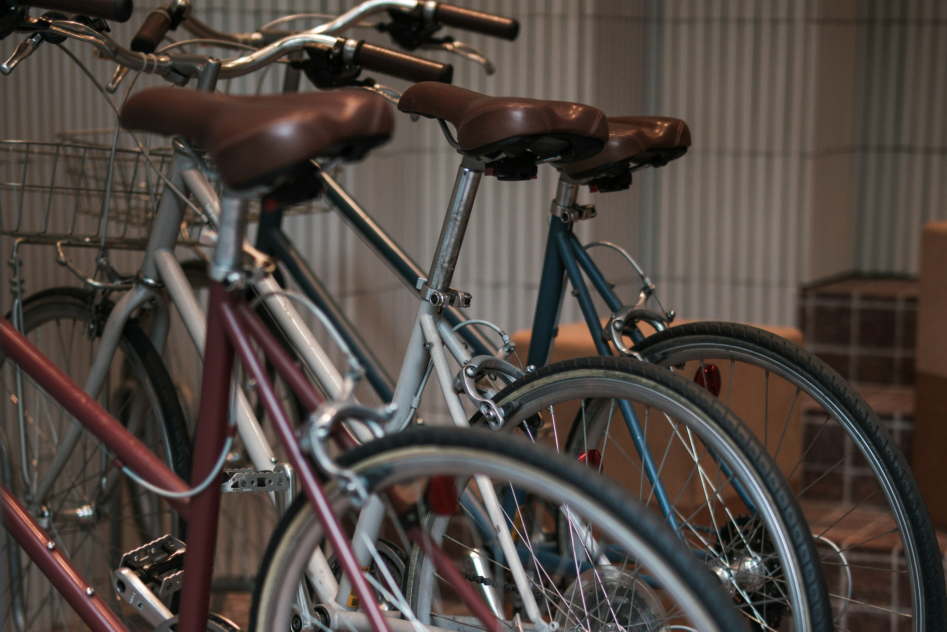 Interior scene of bicycles lined up with brown seats and different colored frames