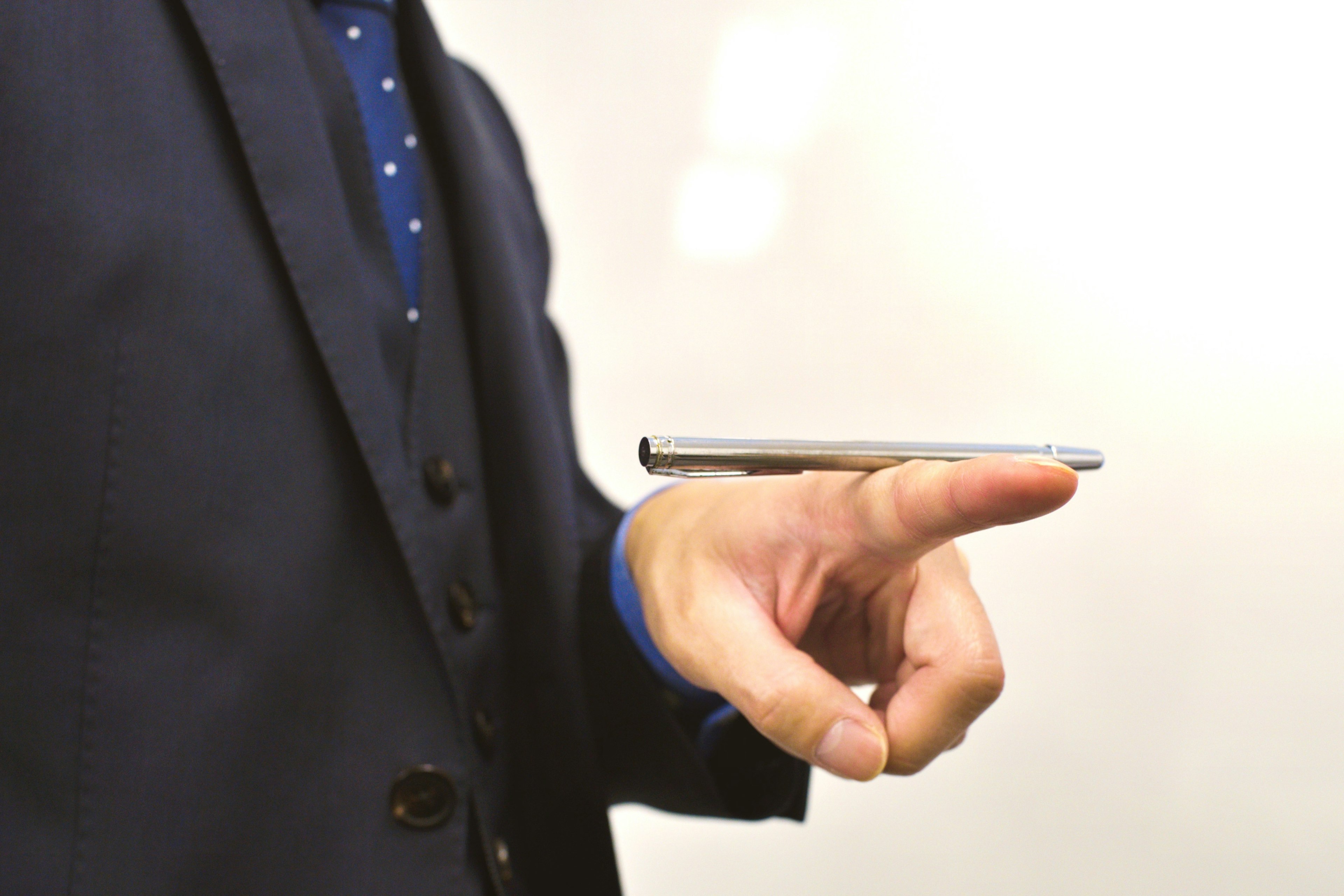 A man in a suit balancing a smartphone on his fingertip