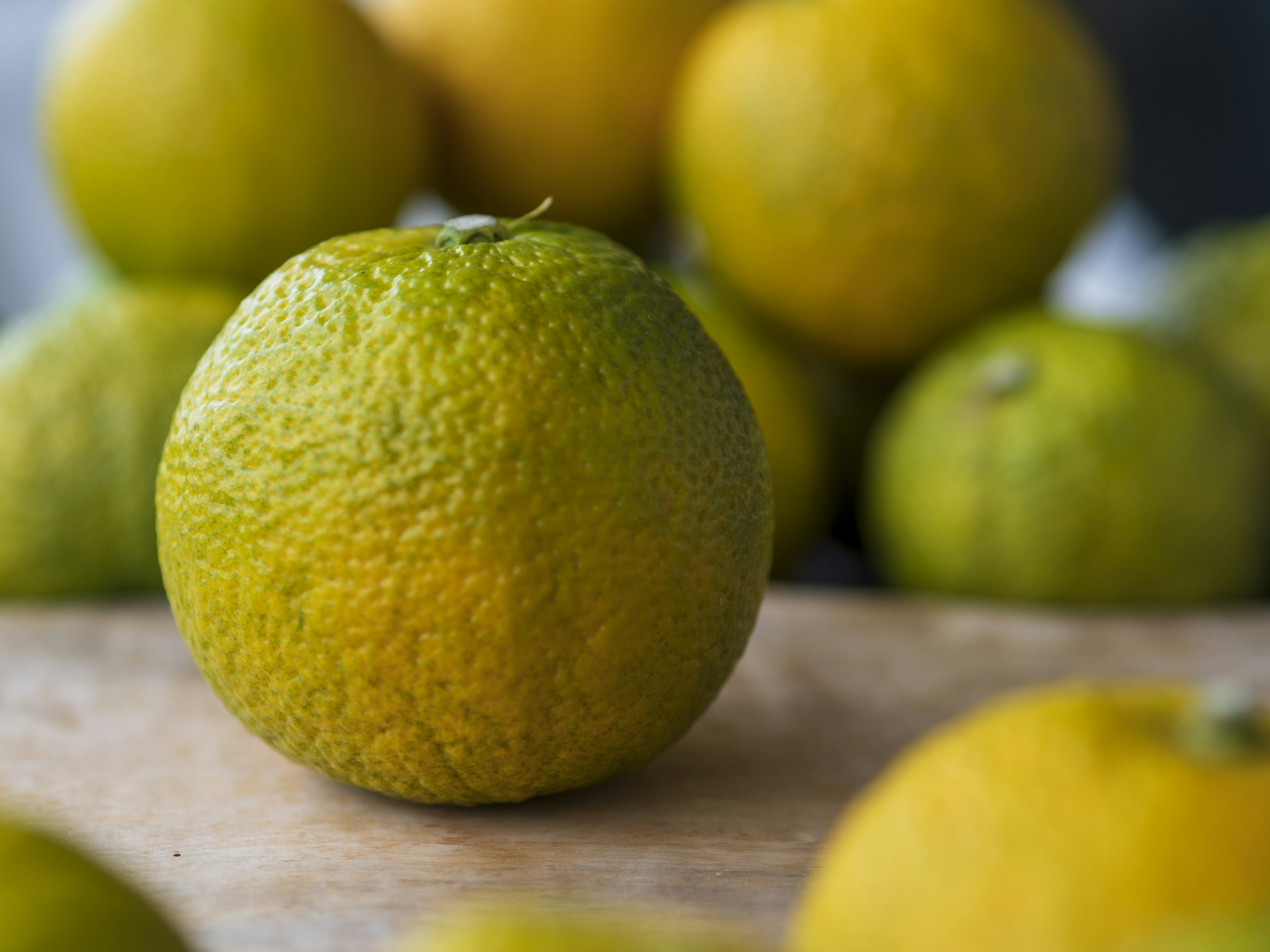 Green citrus fruits placed on a wooden table