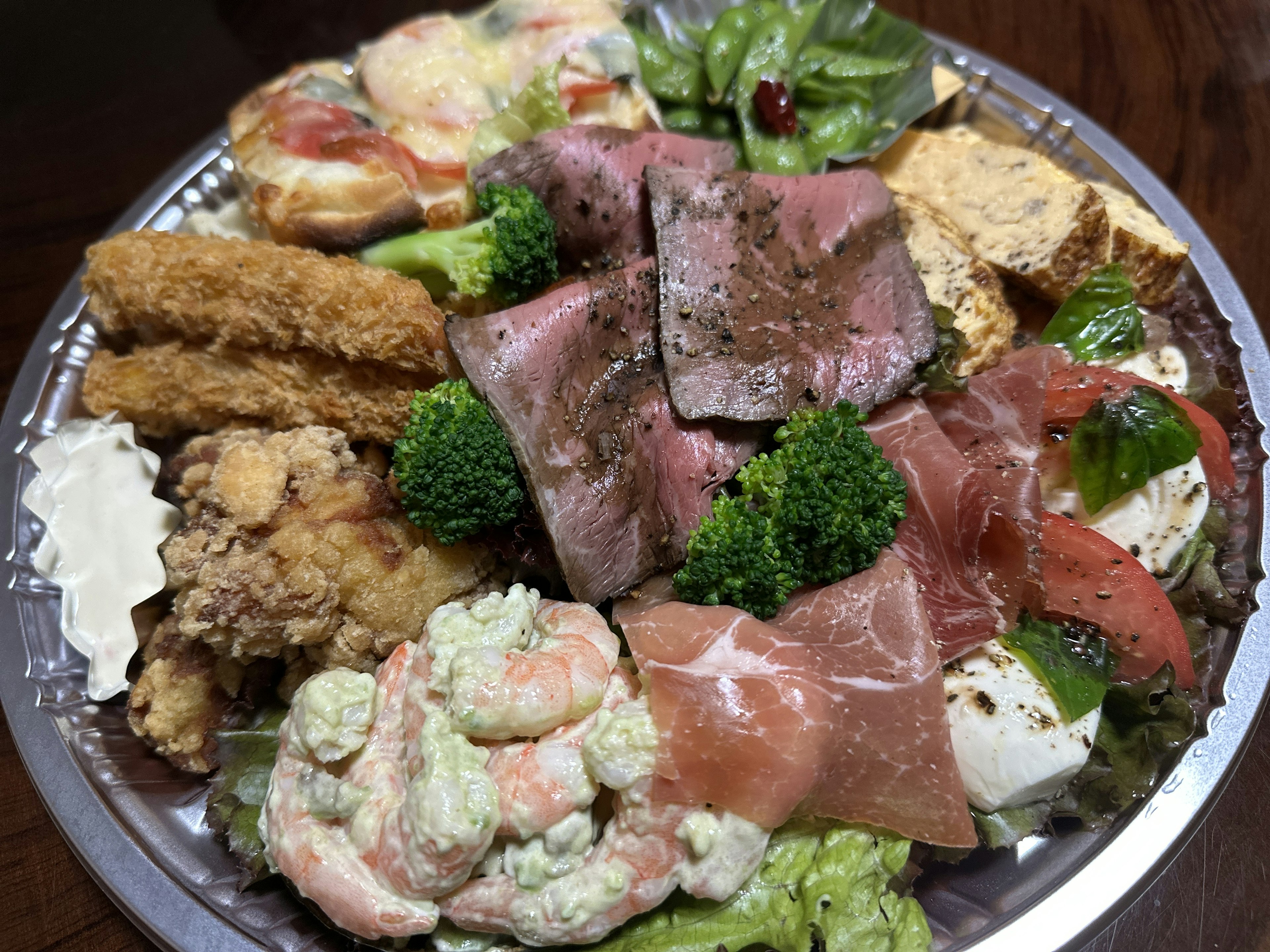 A platter of assorted dishes featuring roasted beef fried chicken shrimp and salad