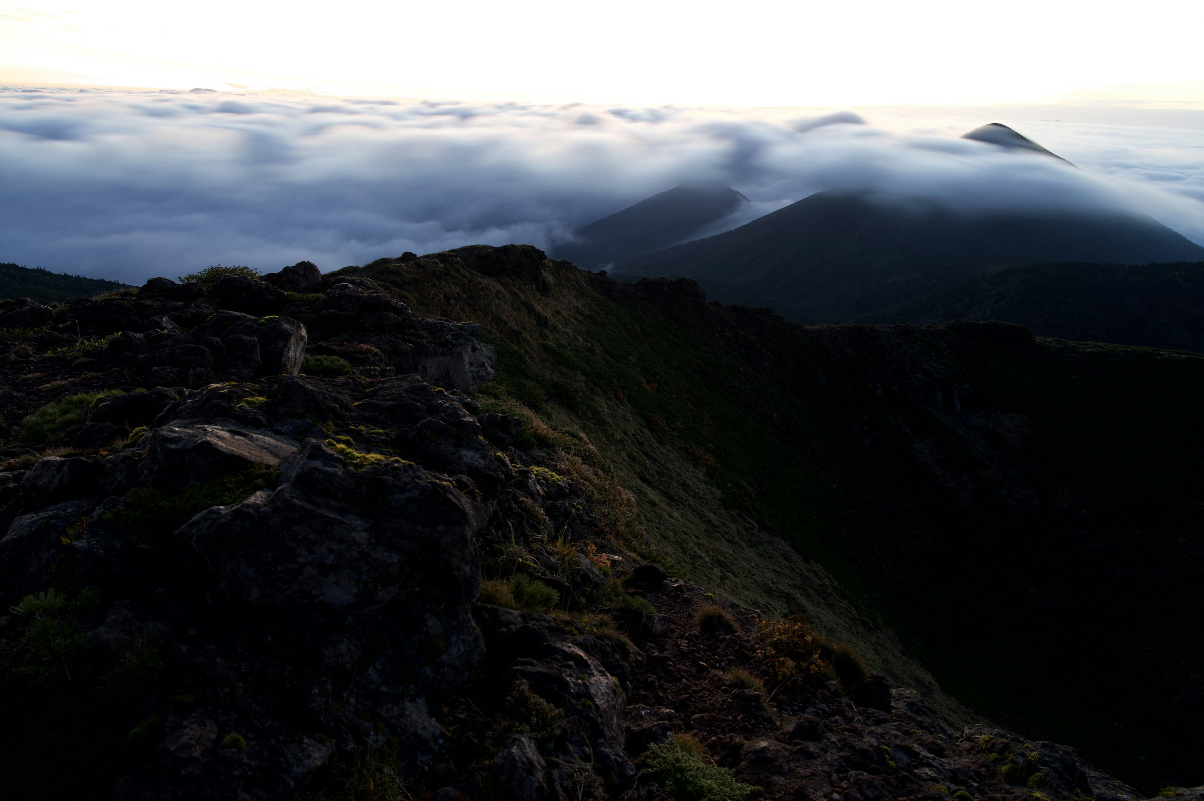 Ridge montano con un mare di nuvole sotto una dolce luce dell'alba