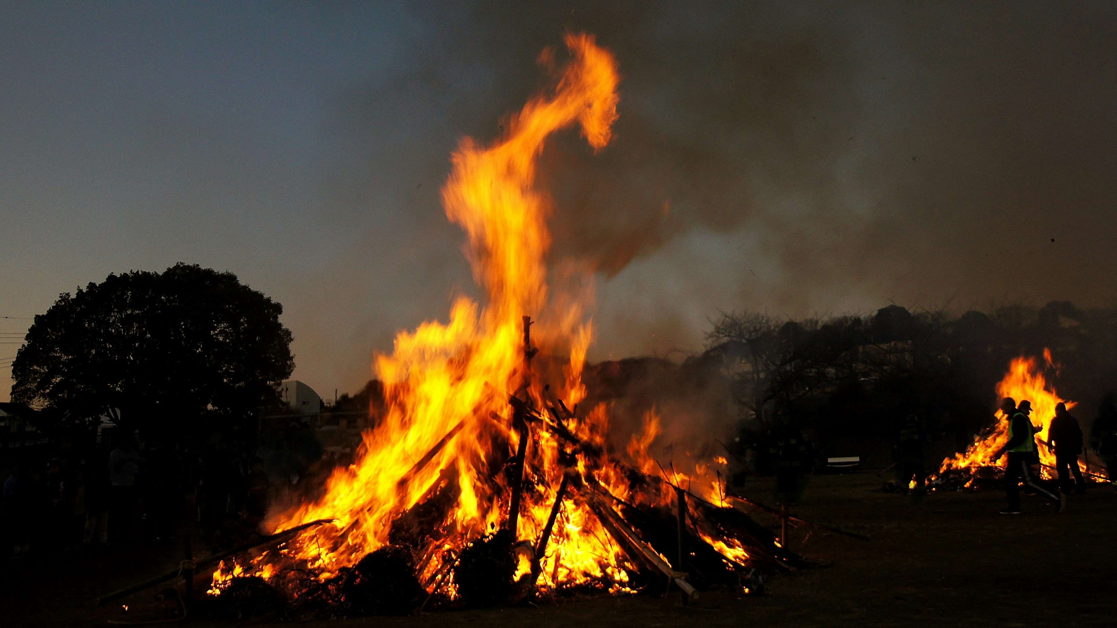 Großes Lagerfeuer brennt unter dem Nachthimmel mit umliegenden Bäumen