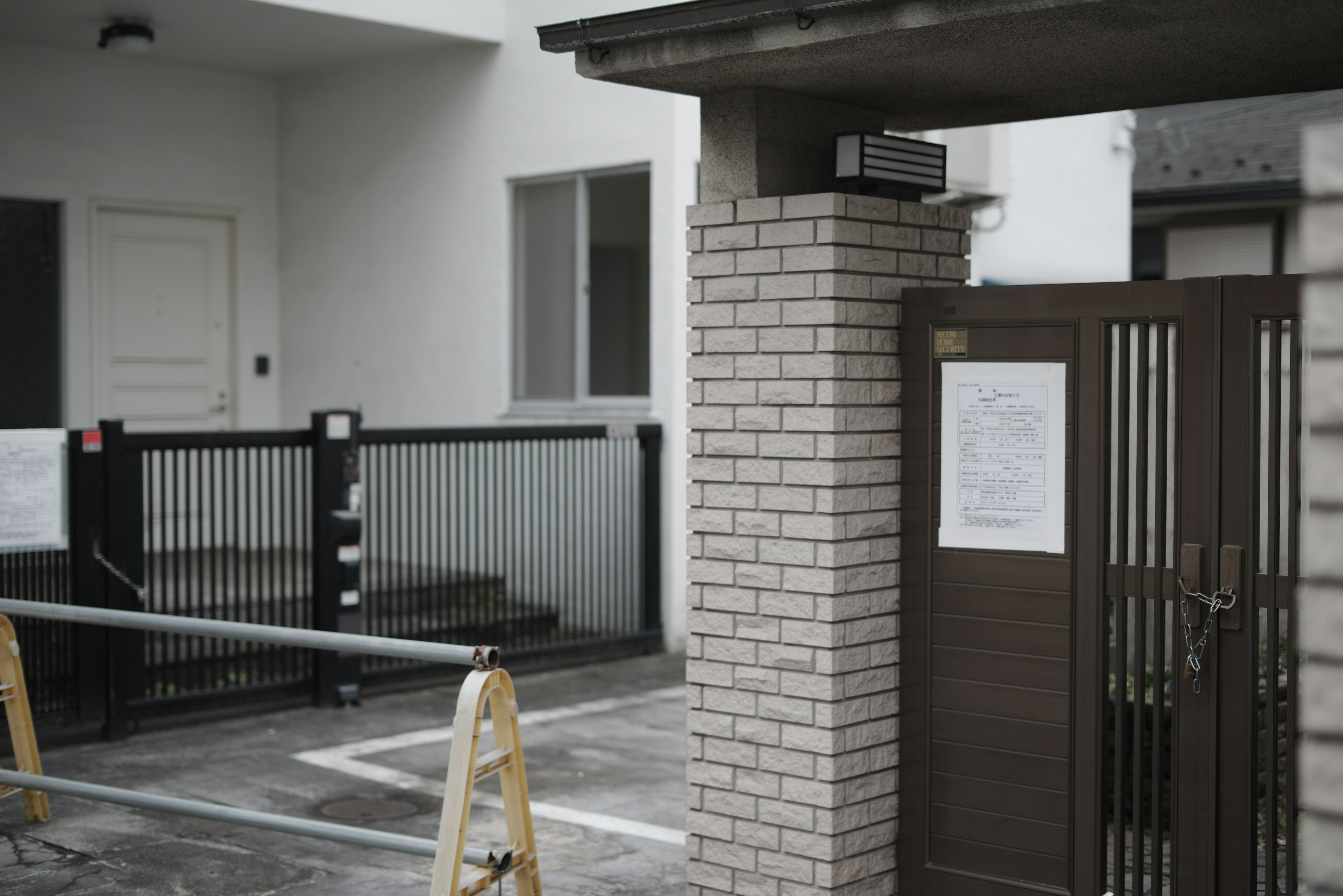 Entrée d'un bâtiment avec des murs blancs et une clôture noire panneau d'avertissement d'un côté