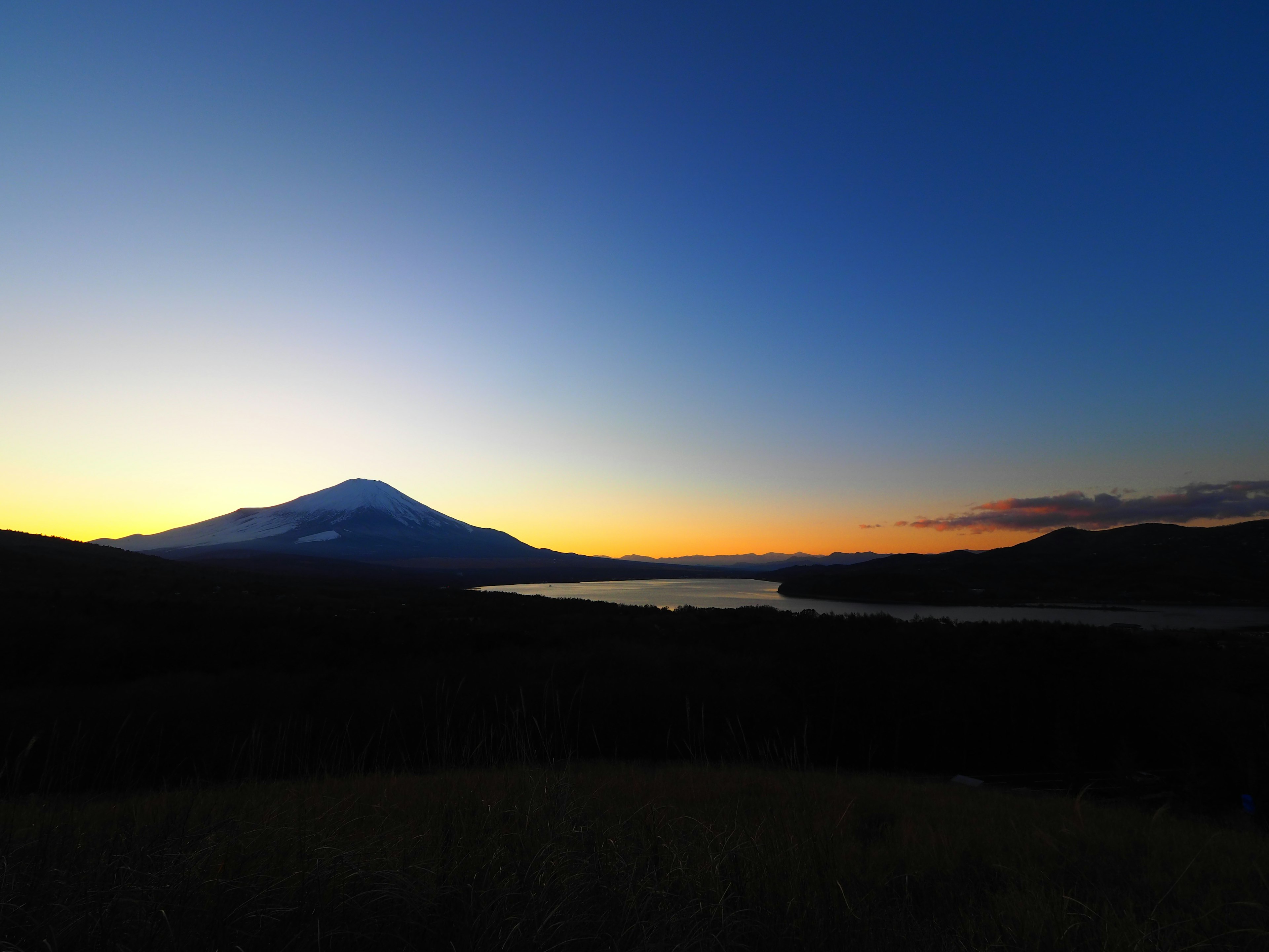 Malersicher Blick auf einen Berg und einen See bei Sonnenuntergang mit Farbverlauf am Himmel