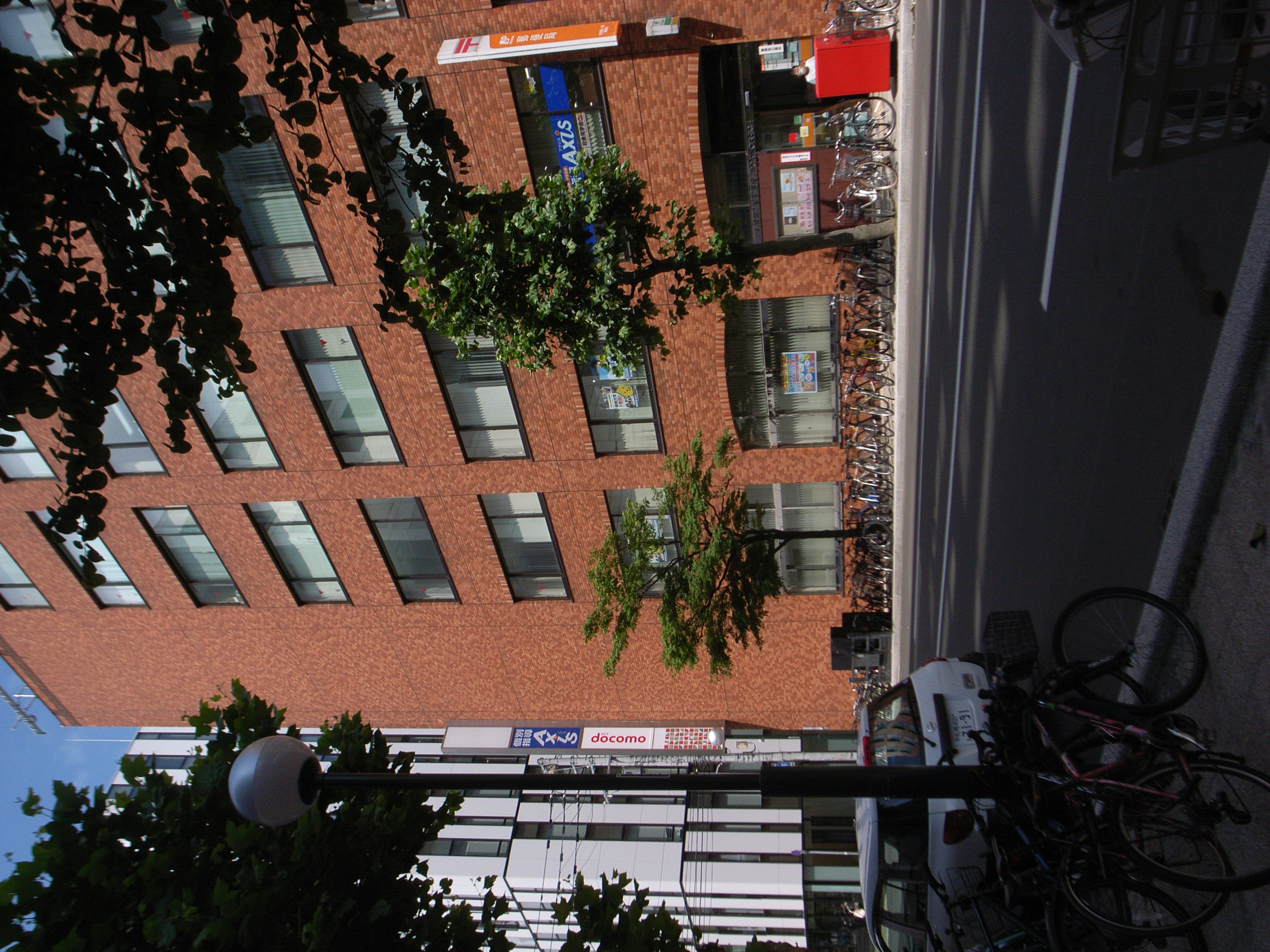 Vue de rue avec un bâtiment en briques rouges et des vélos garés