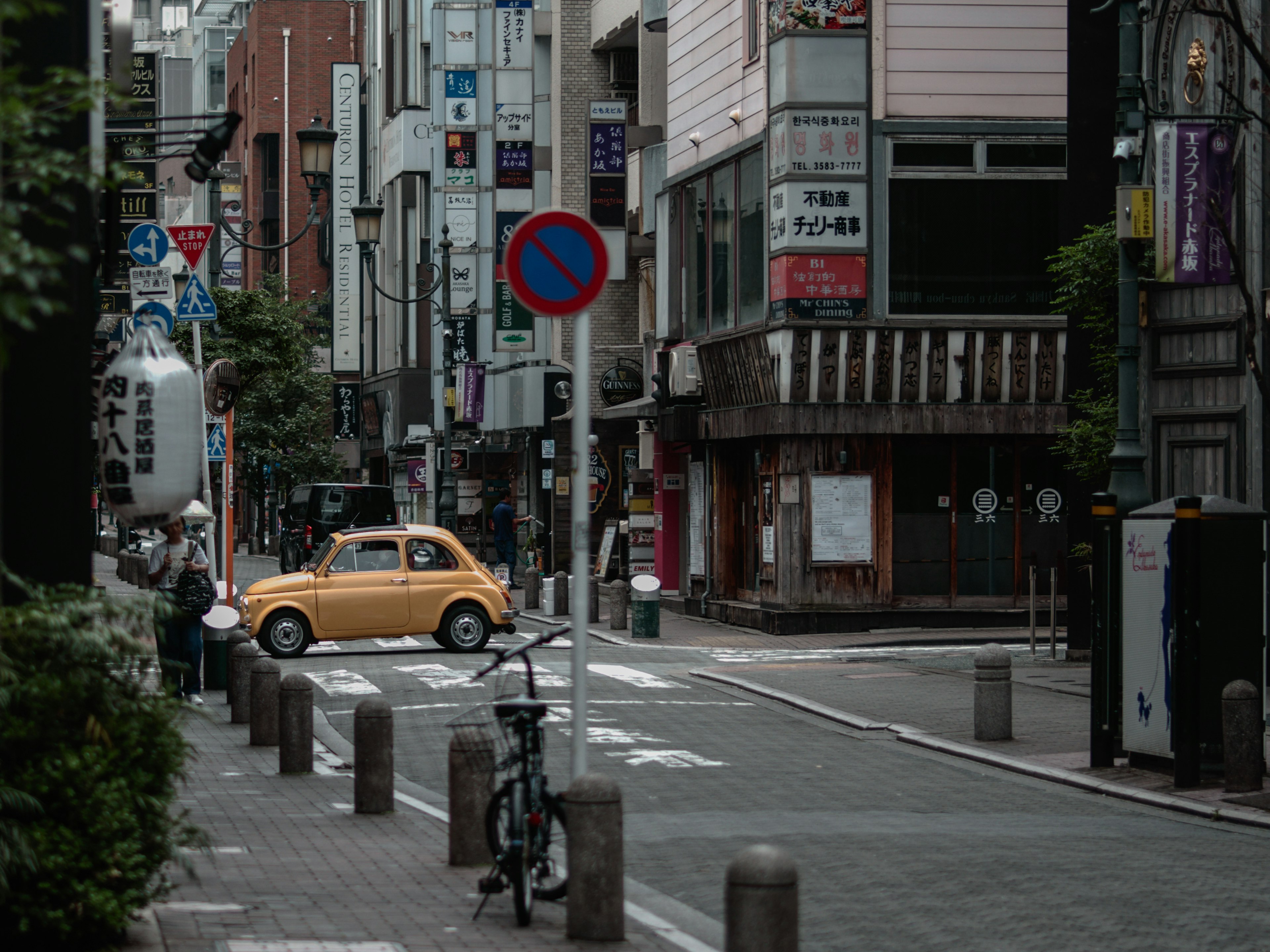 東京的一條安靜街道上有一輛黃色汽車和一輛腳踏車