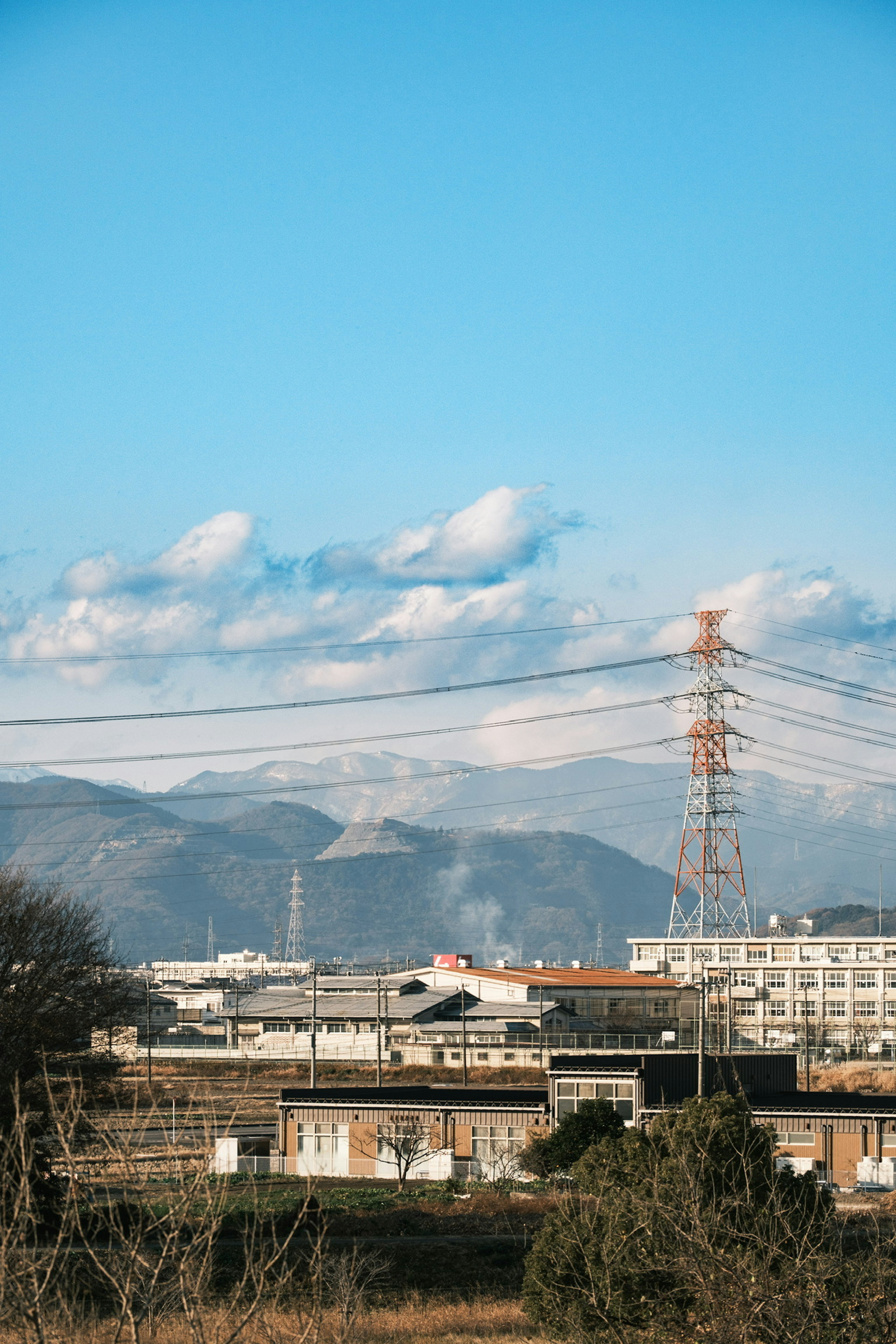 Paisaje industrial con cielo azul y nubes montañas distantes al fondo