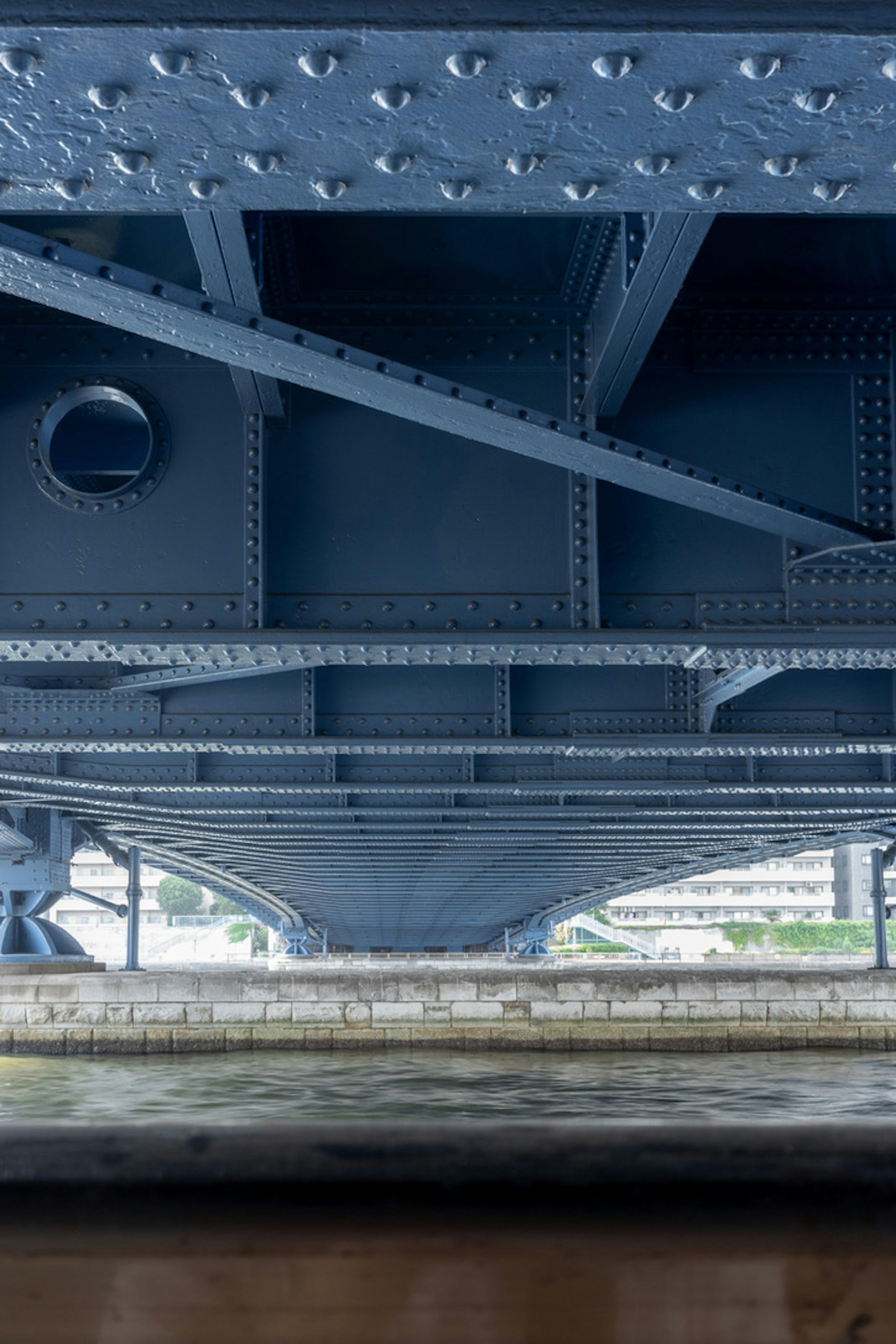 Dettagli strutturali di un ponte blu visti da sotto con travi in ferro