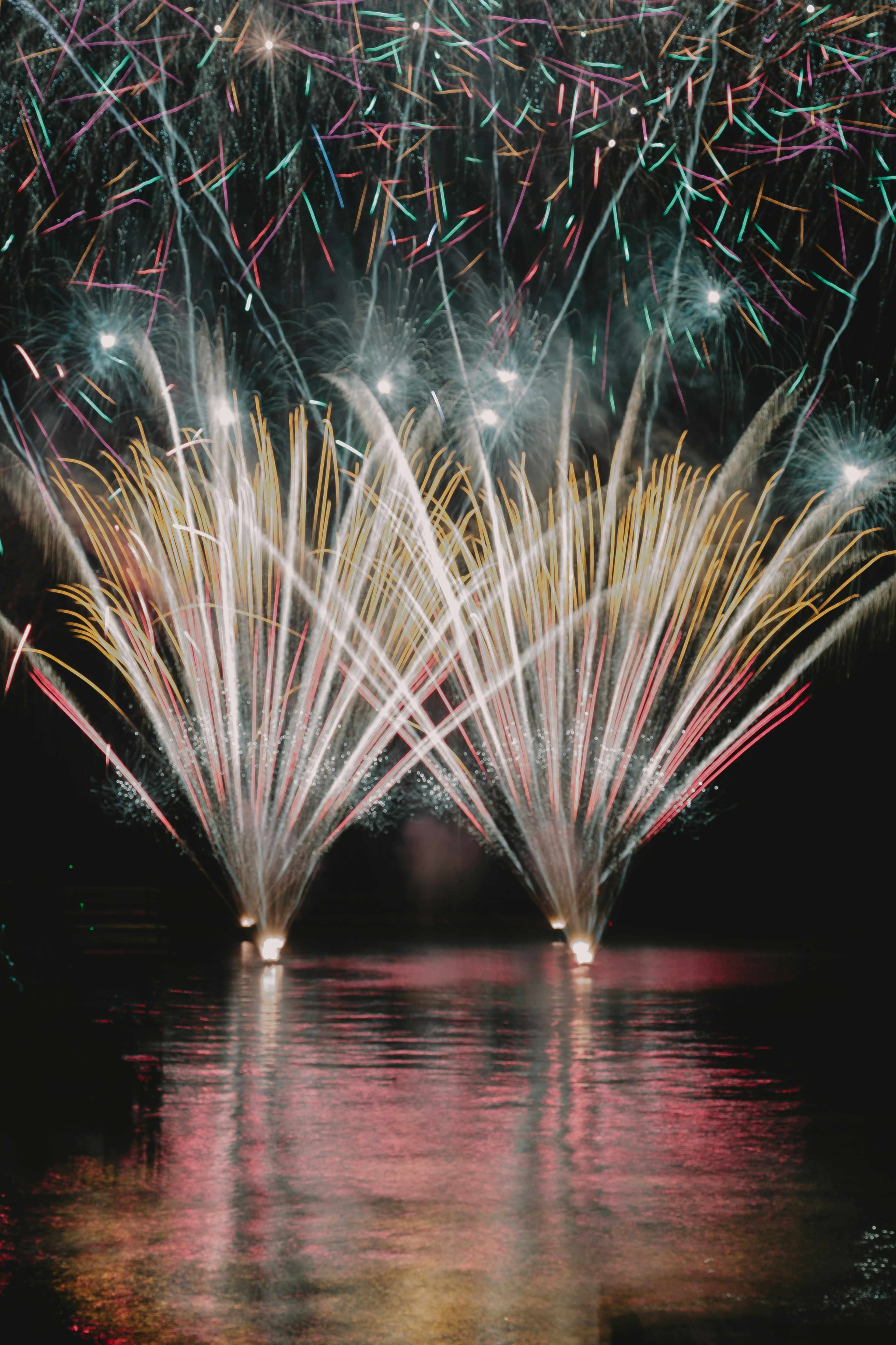 Vibrant fireworks display reflecting on the water at night