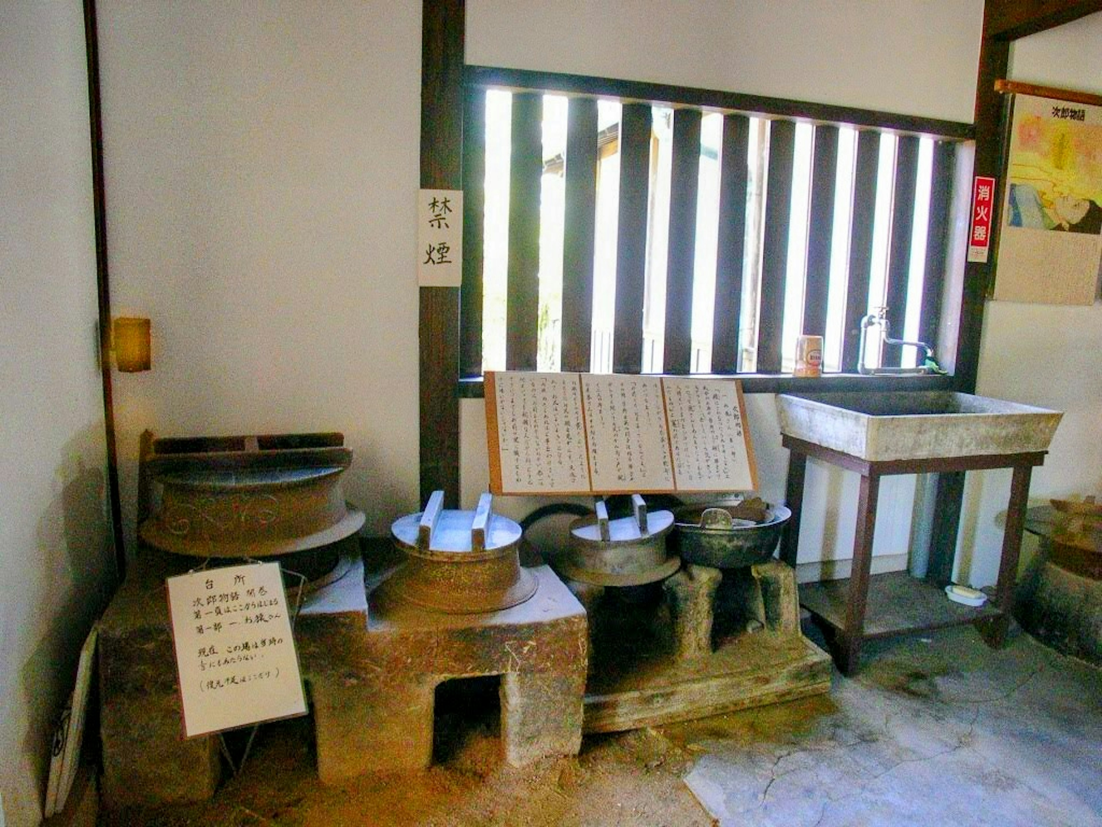 Interior view featuring old stone grinding wheels with natural light through the window