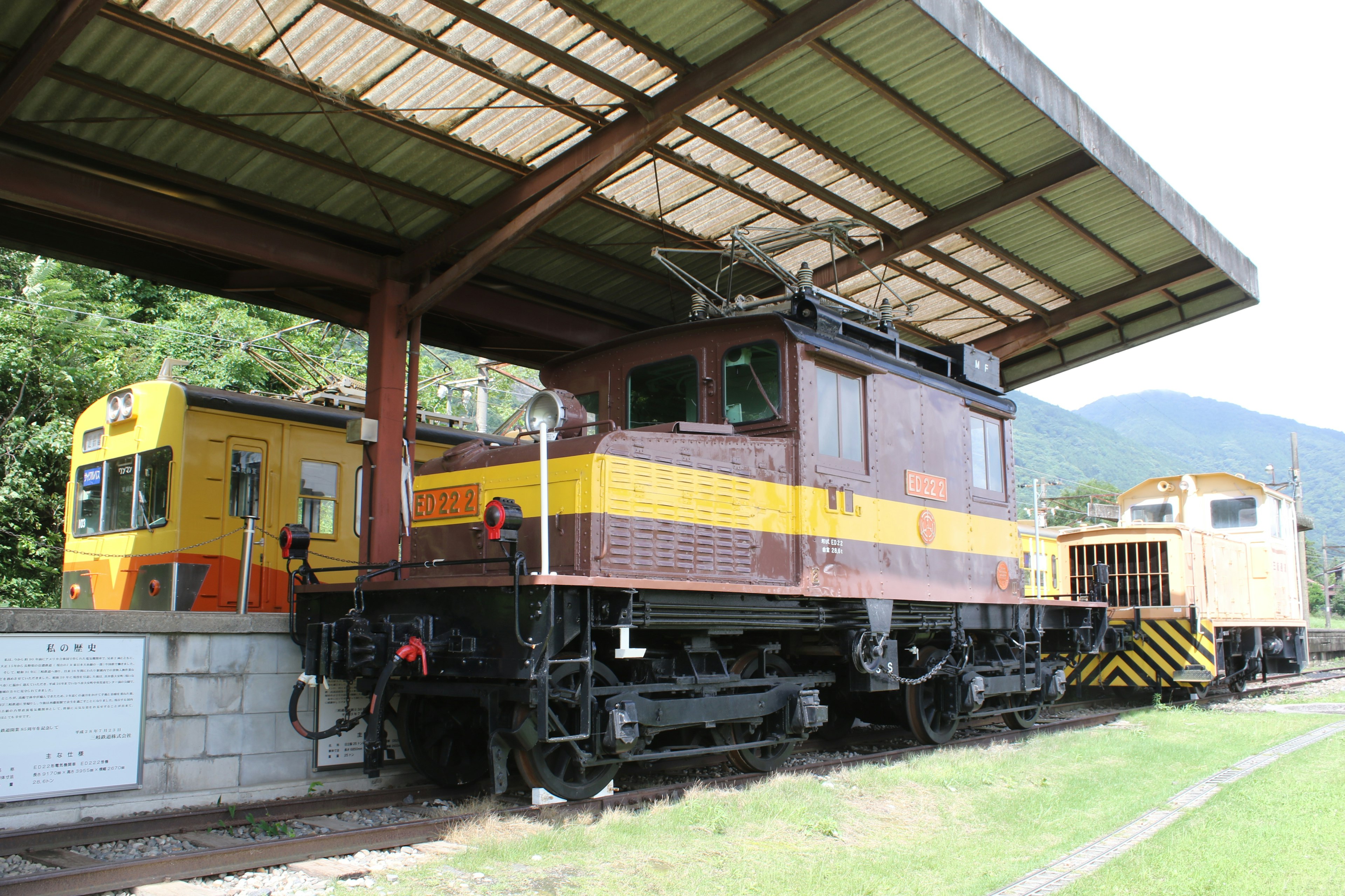 Old electric locomotive at a train station with surrounding scenery