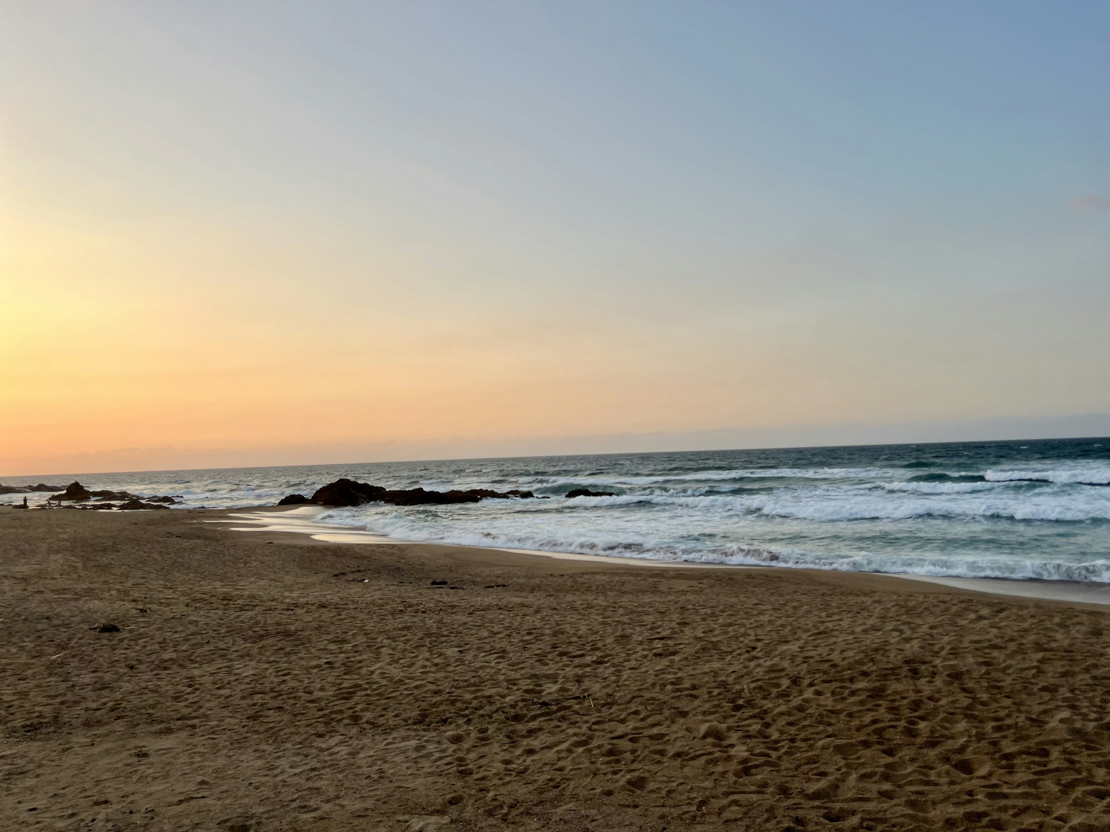 Schöne Strand-Sonnenuntergangsszene Wellen schlagen gegen den Sand sanfte Himmelstöne