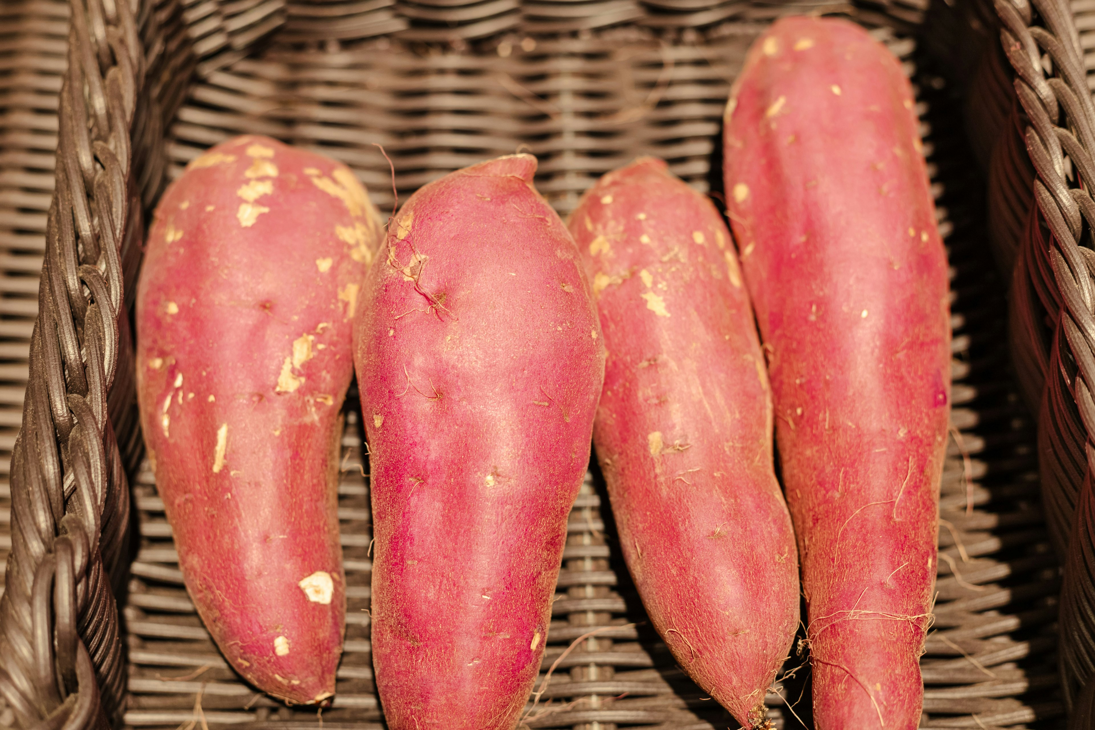 Four red sweet potatoes placed in a wicker basket