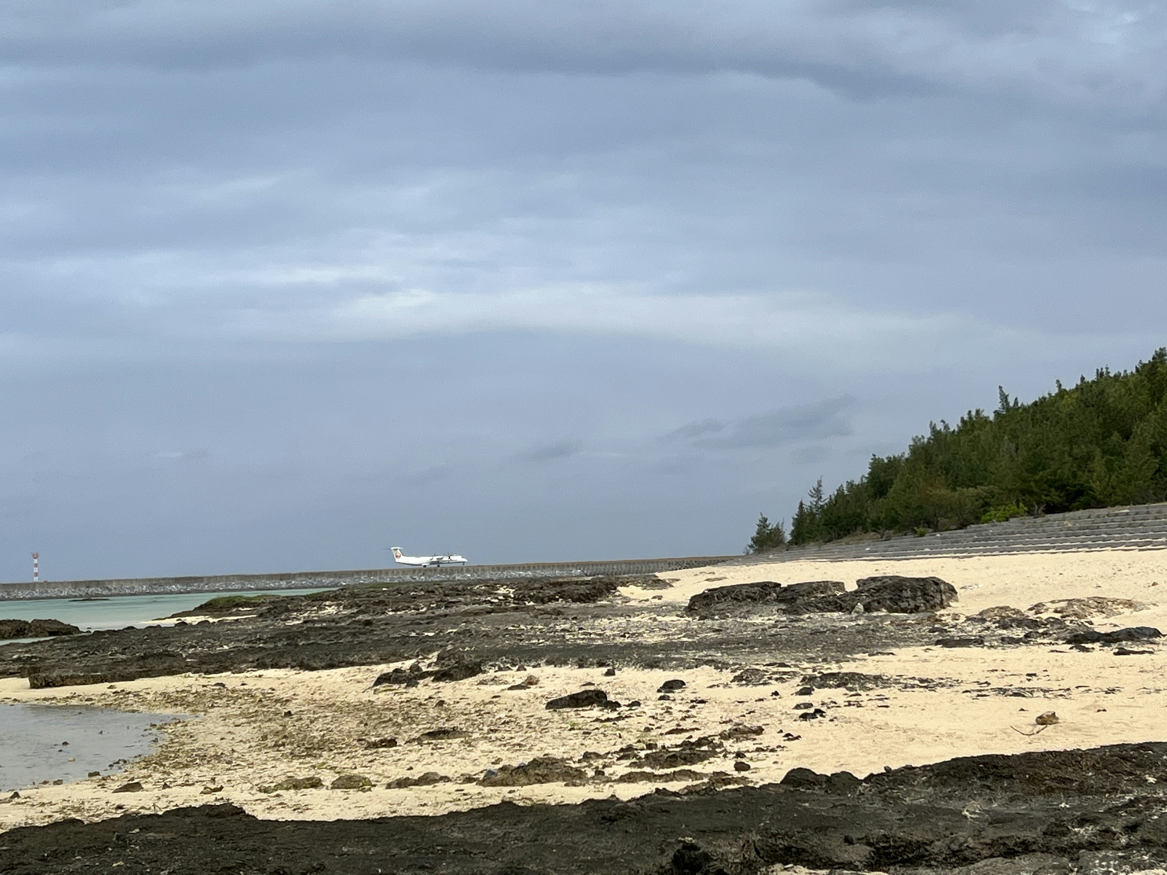 Pemandangan pantai tenang dengan garis pantai dan formasi batu