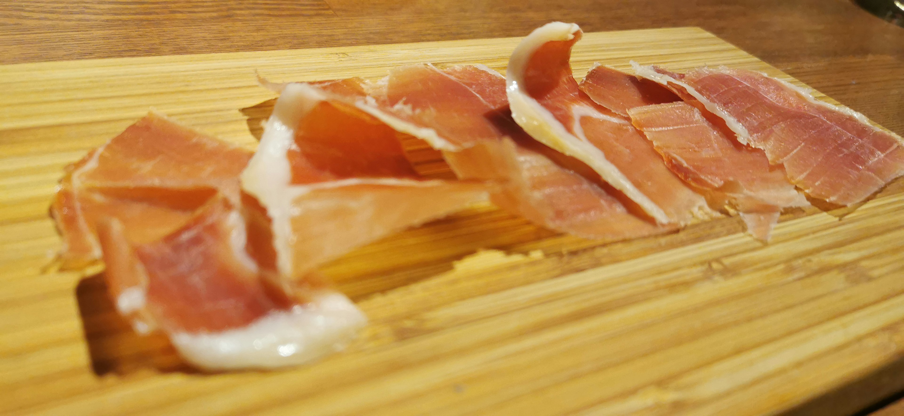 Sliced prosciutto arranged on a wooden board