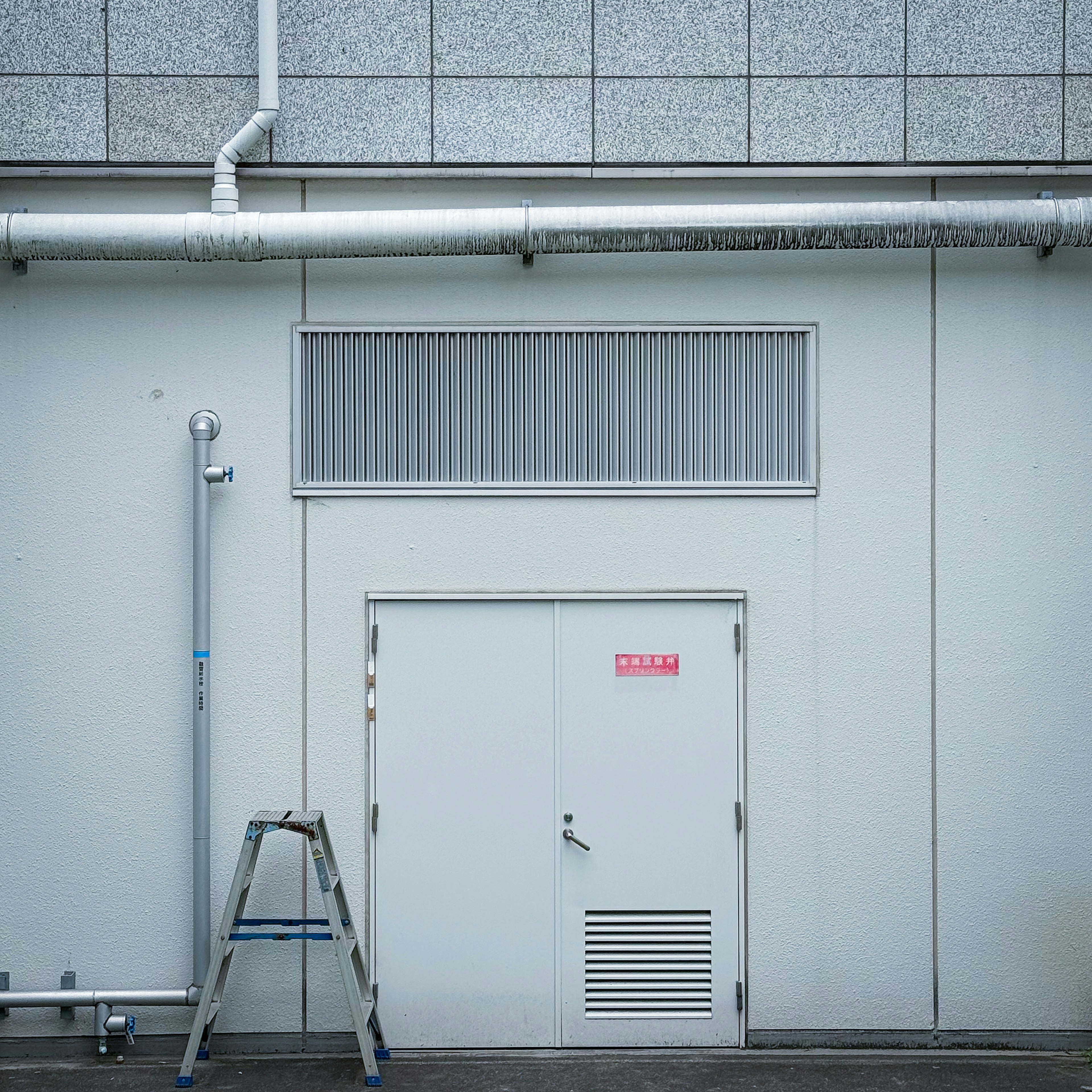 Exterior of a building with a small door and window on a white wall