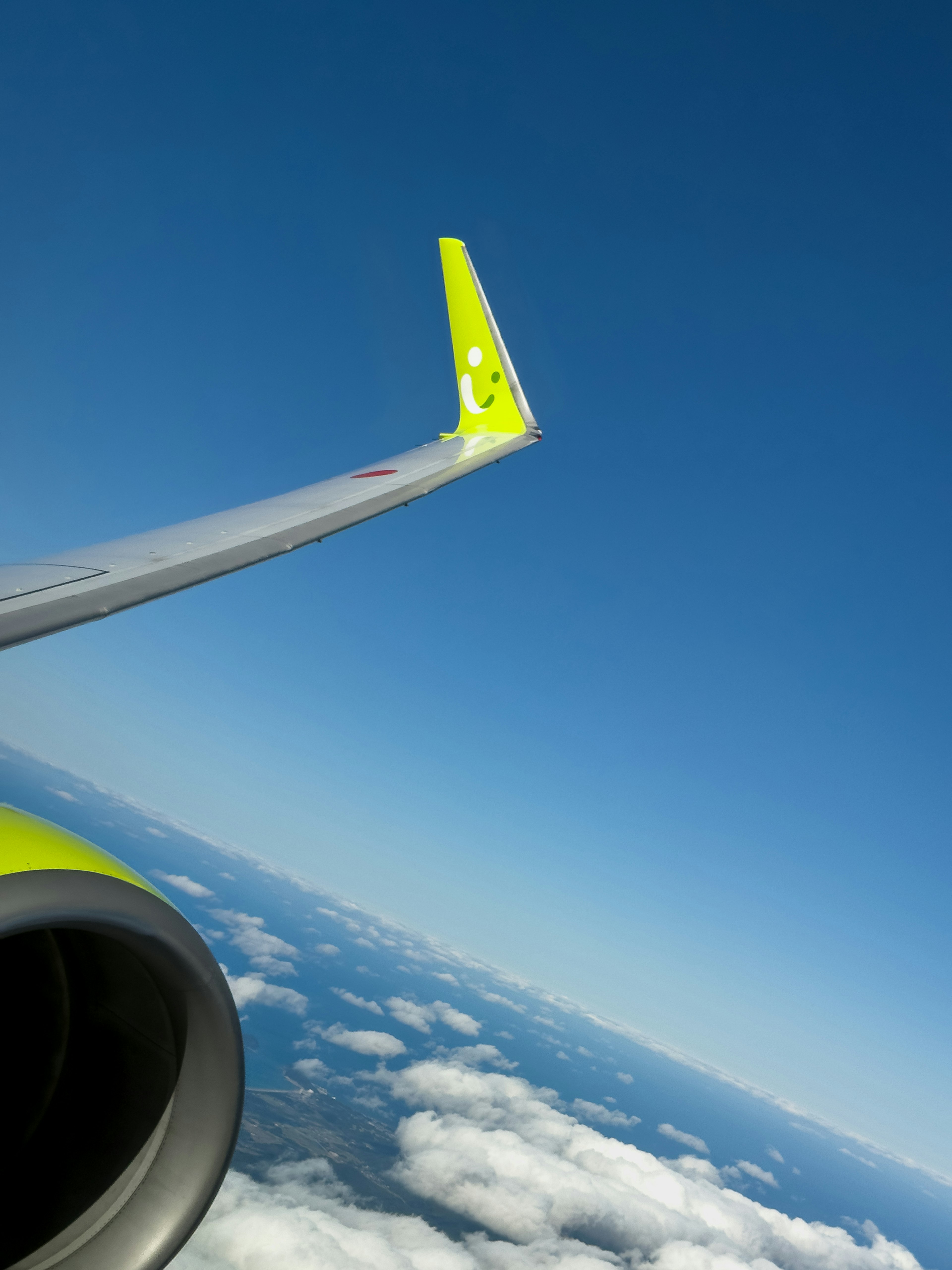 Airplane wing and engine visible against a clear blue sky