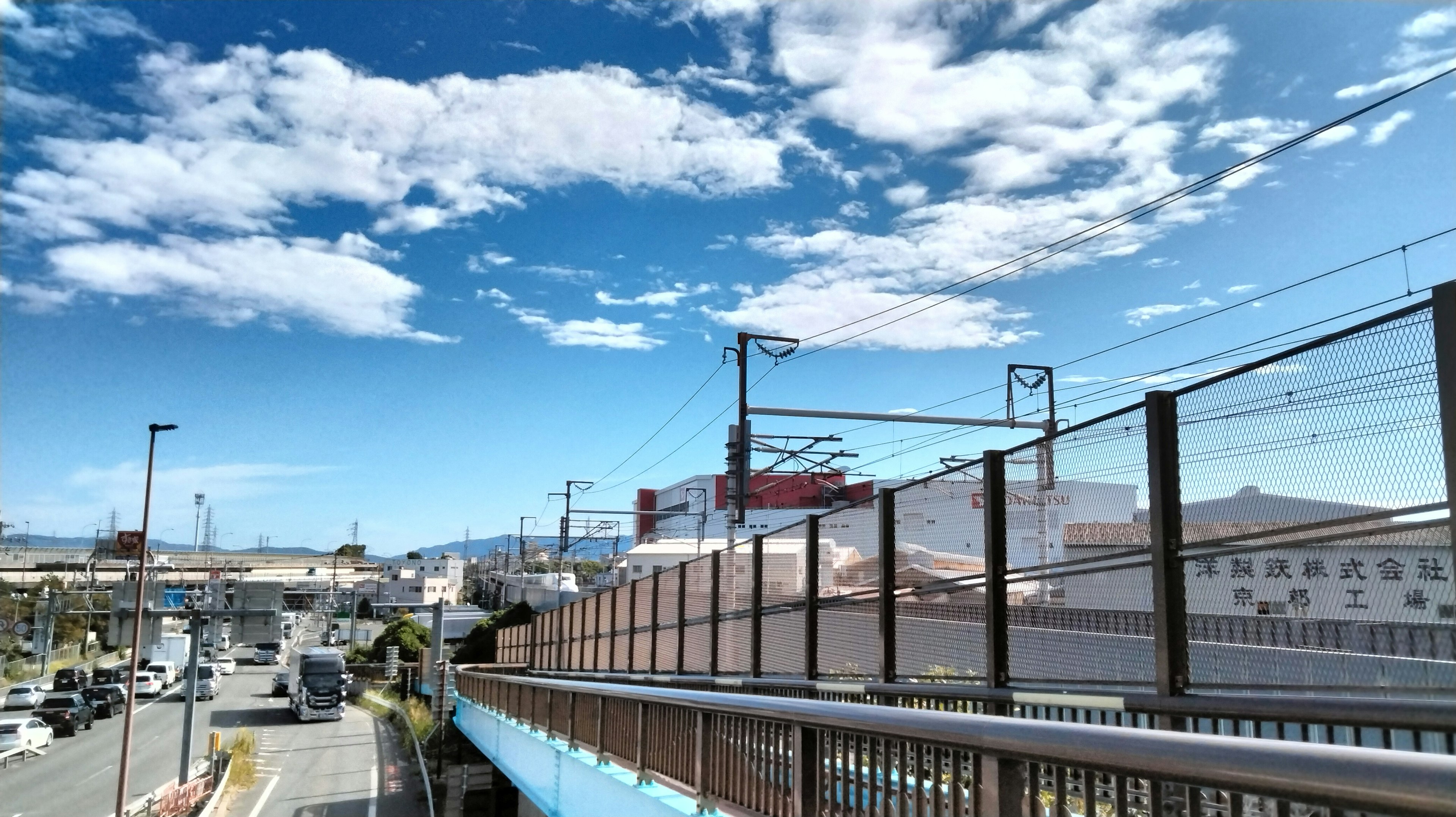 Pemandangan indah dengan langit biru dan awan putih menampilkan rel kereta dan bangunan