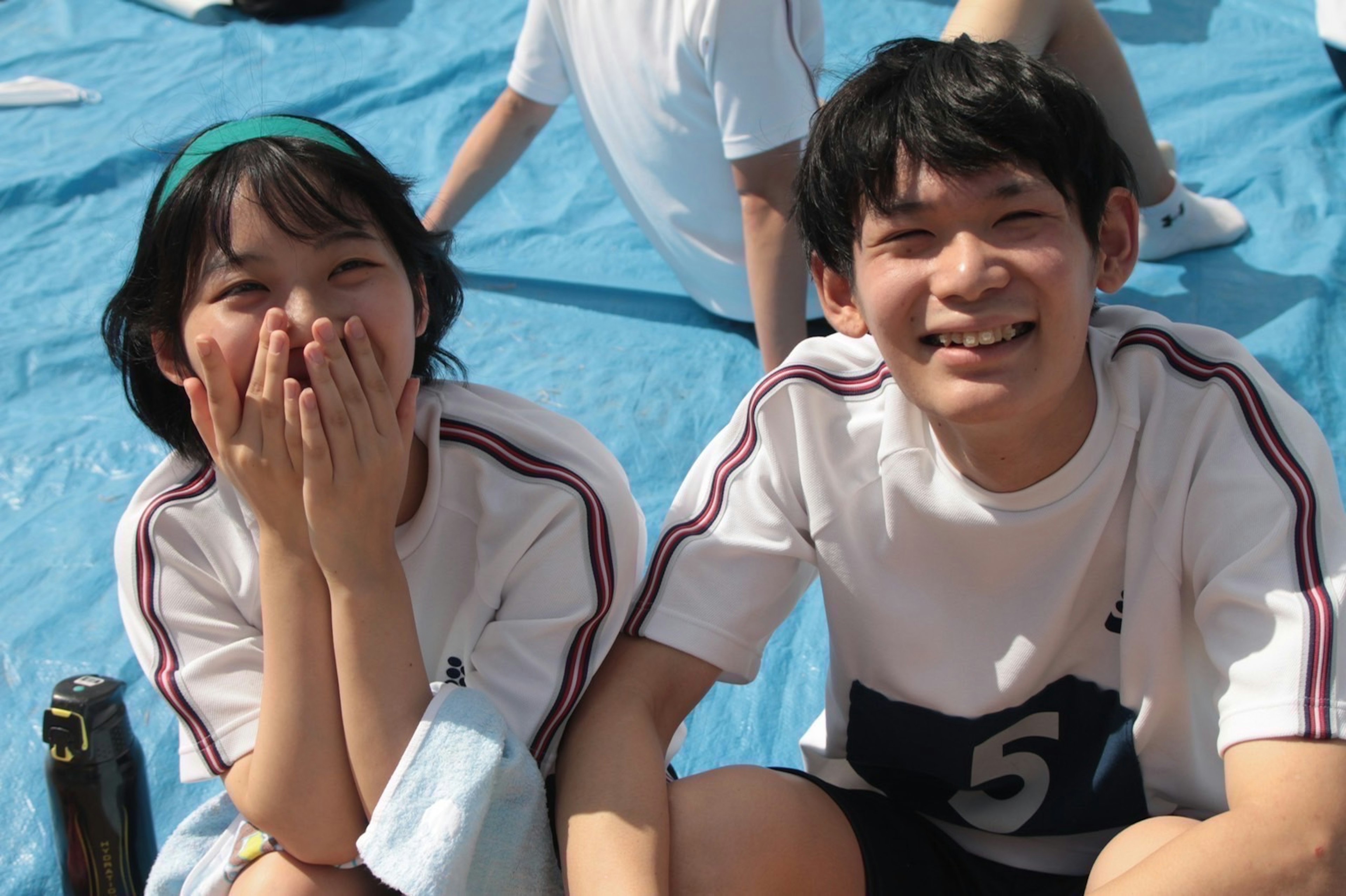 運動会の青いシートの上で笑顔の少年少女