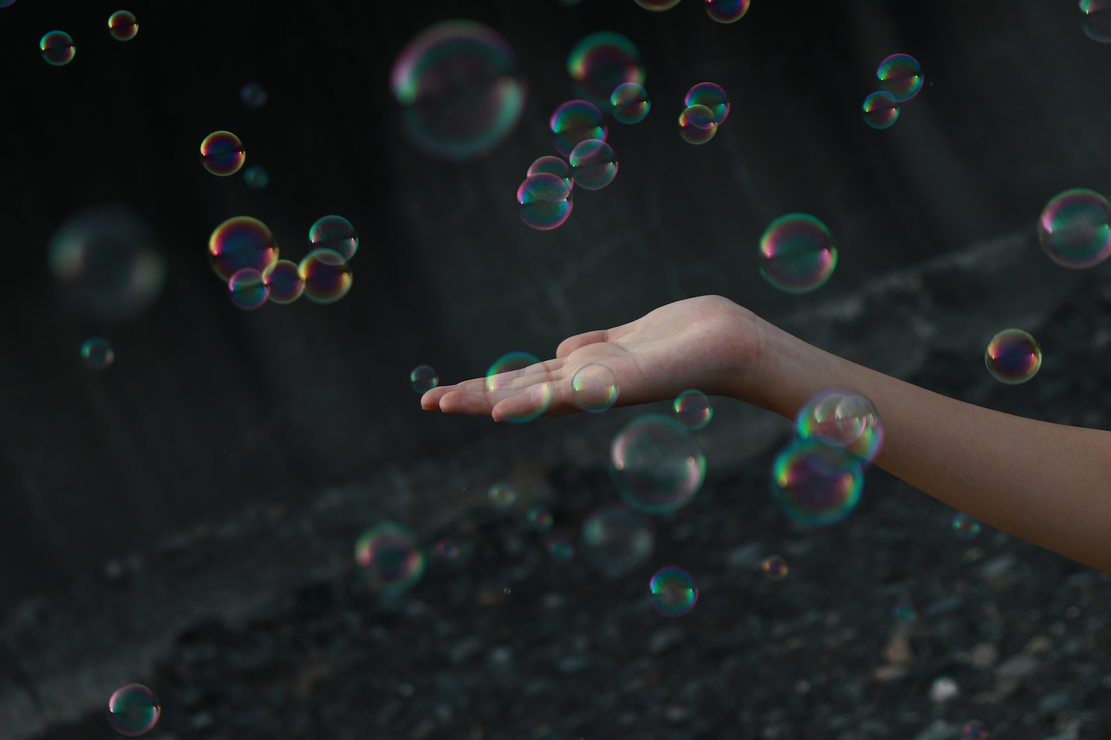 A hand reaching out with floating bubbles against a dark background