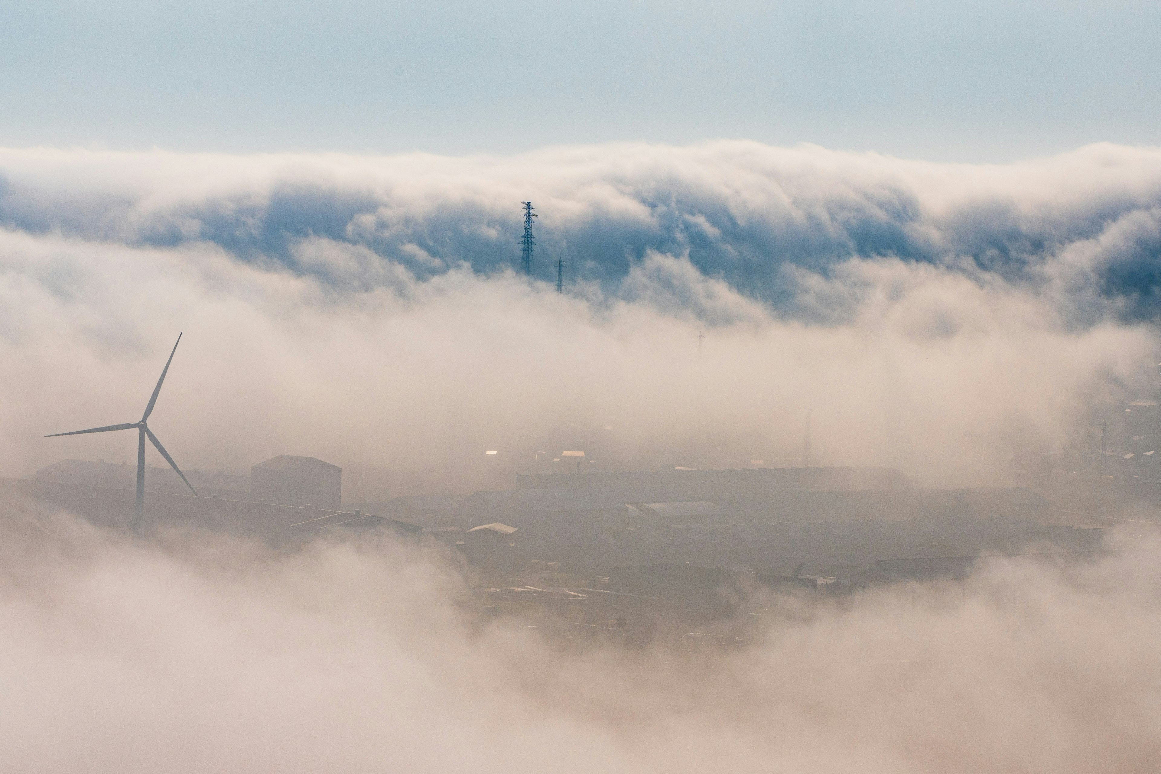 Escena de turbina eólica y fábrica envuelta en niebla