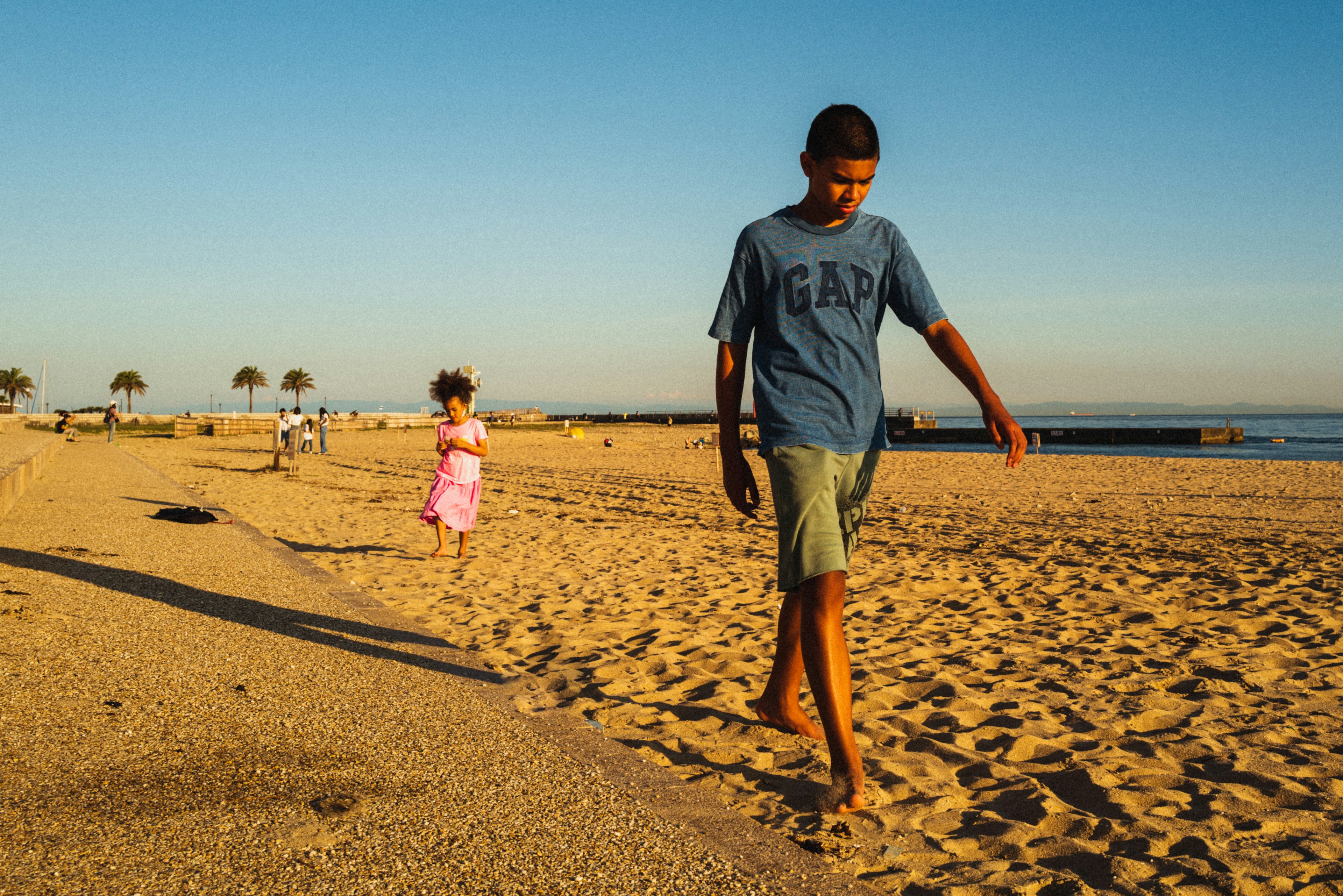 Adegan seorang anak laki-laki berjalan dan seorang anak perempuan berlari di pantai