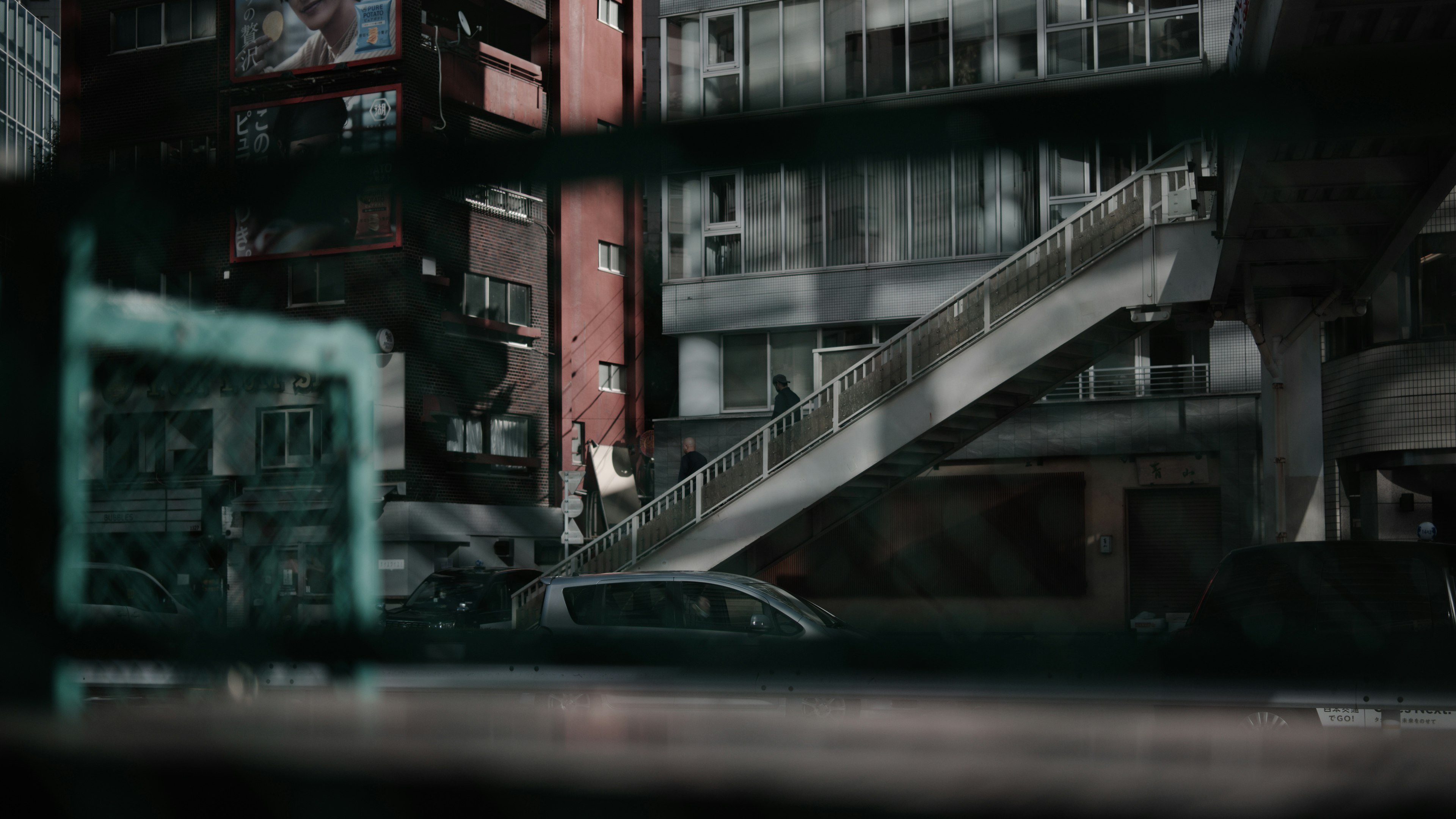 Urban landscape viewed through a window featuring a railway overpass and buildings