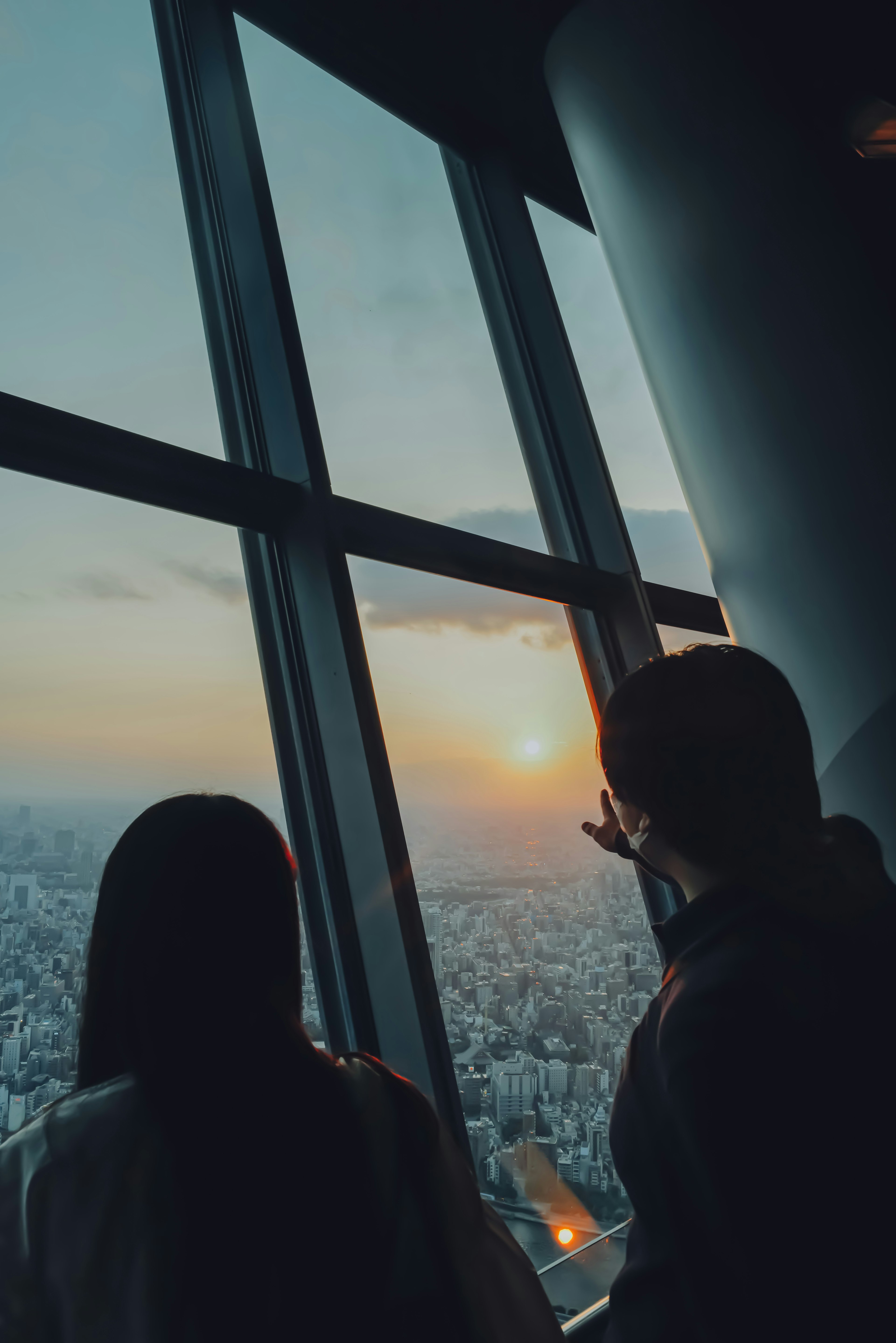 Dos personas mirando el atardecer desde la ventana de un rascacielos