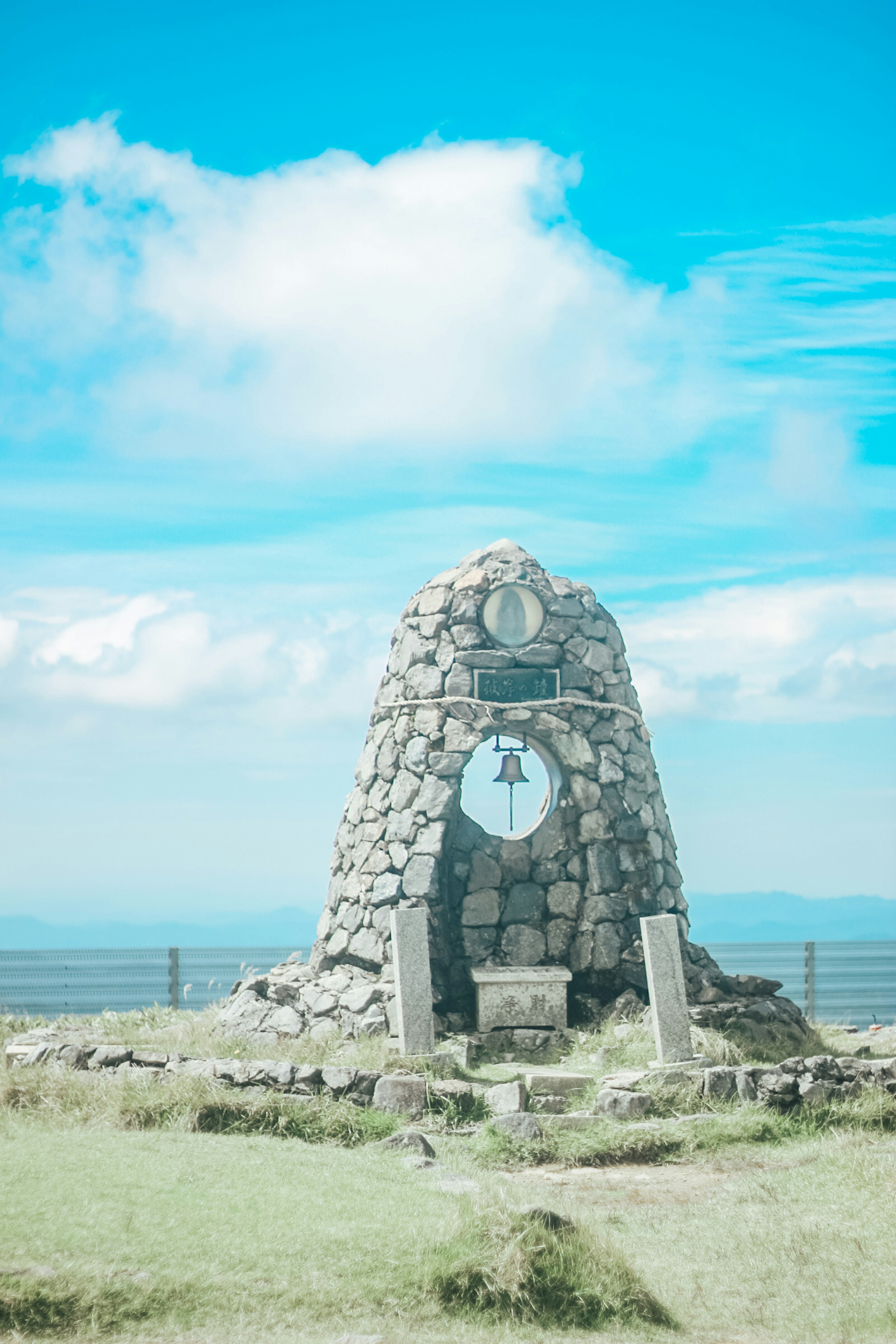 Monumento de piedra con una campana bajo un cielo azul