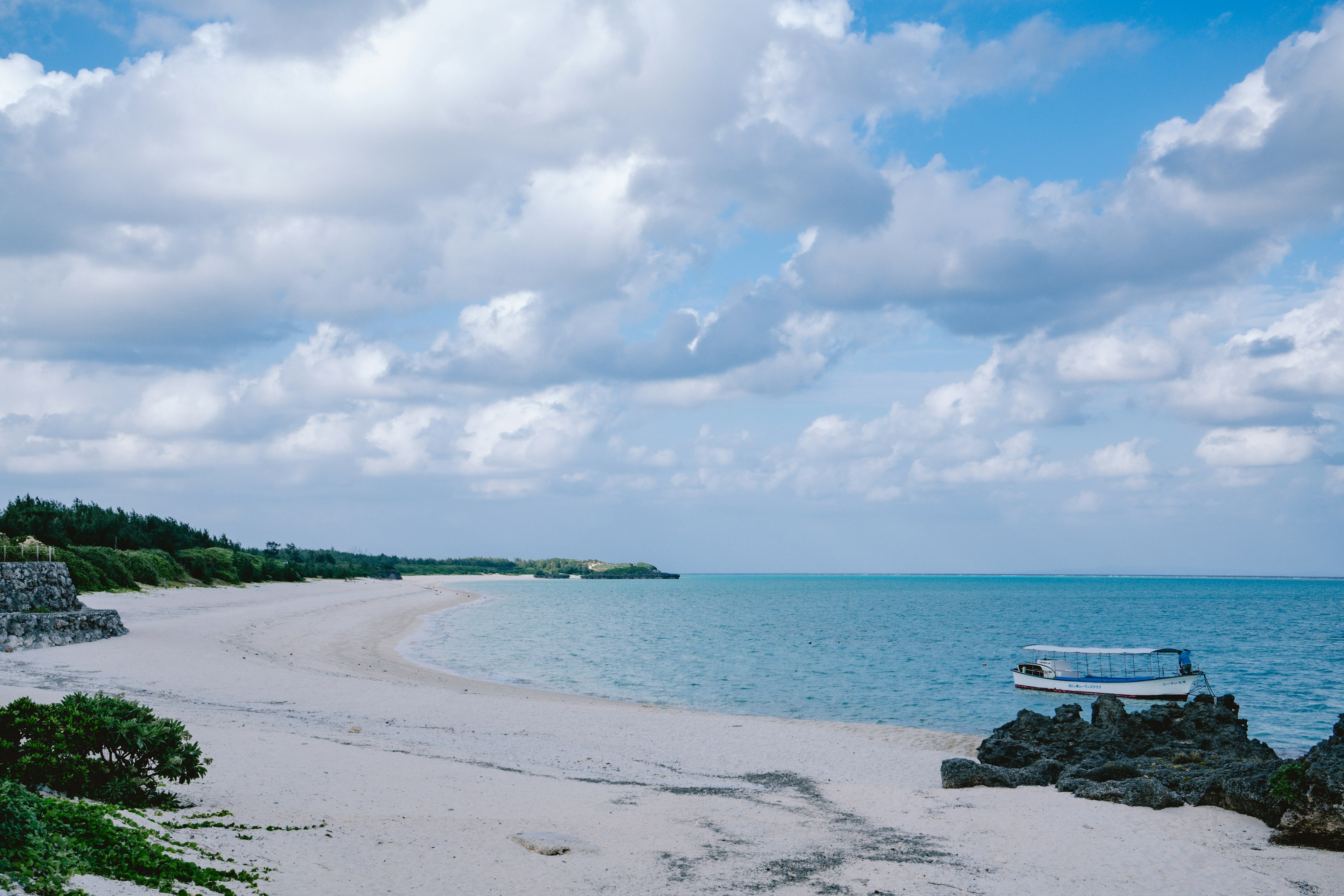 Scenic view of a sandy beach and turquoise water under a cloudy sky